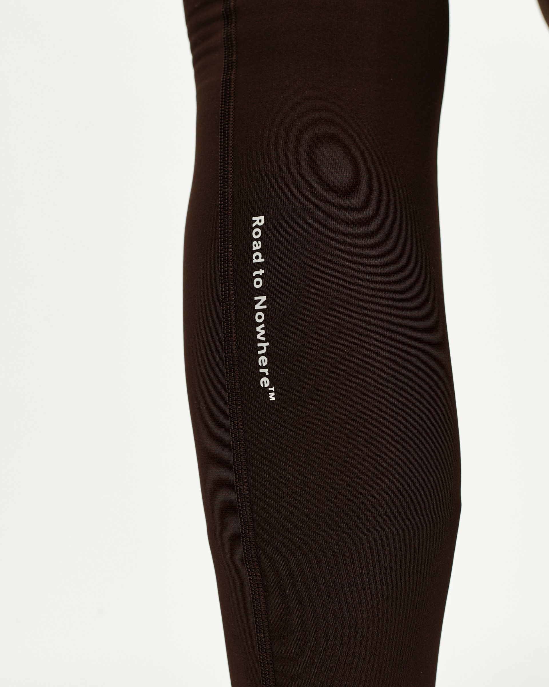 Dark Coffee Mechanism Thermal Long cycling bibs, side detail view with white Road to Nowhere side print
