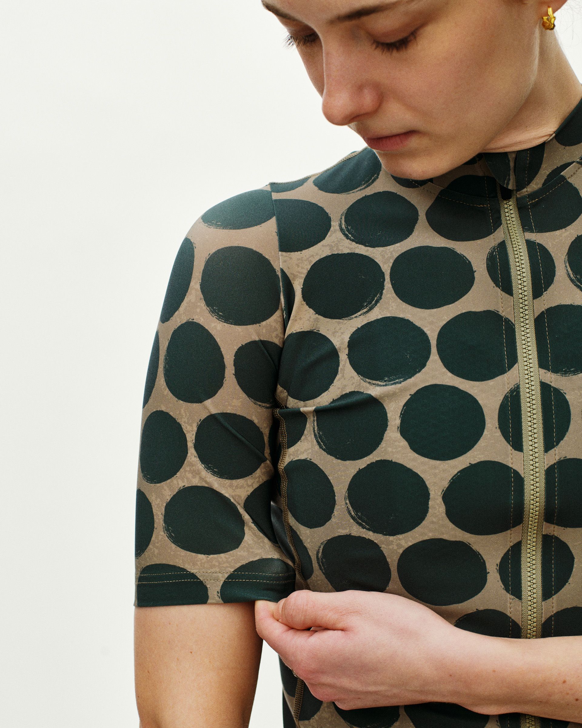 Beige Essential cycling jersey on model with green polka dot pattern and front zip