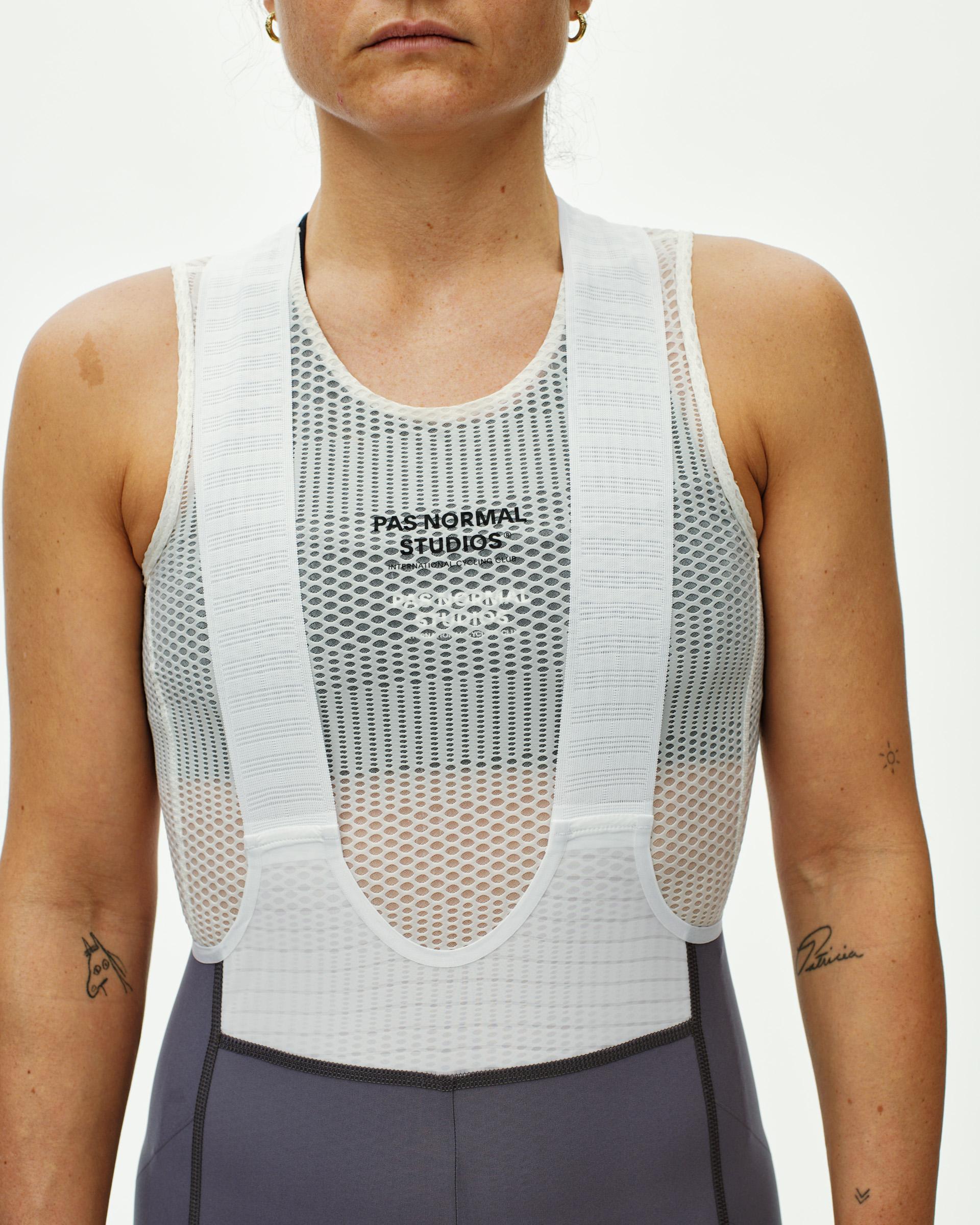 Grey Mechanism Pro women's cycling bibs, front view on model with white mesh base layer over bib straps