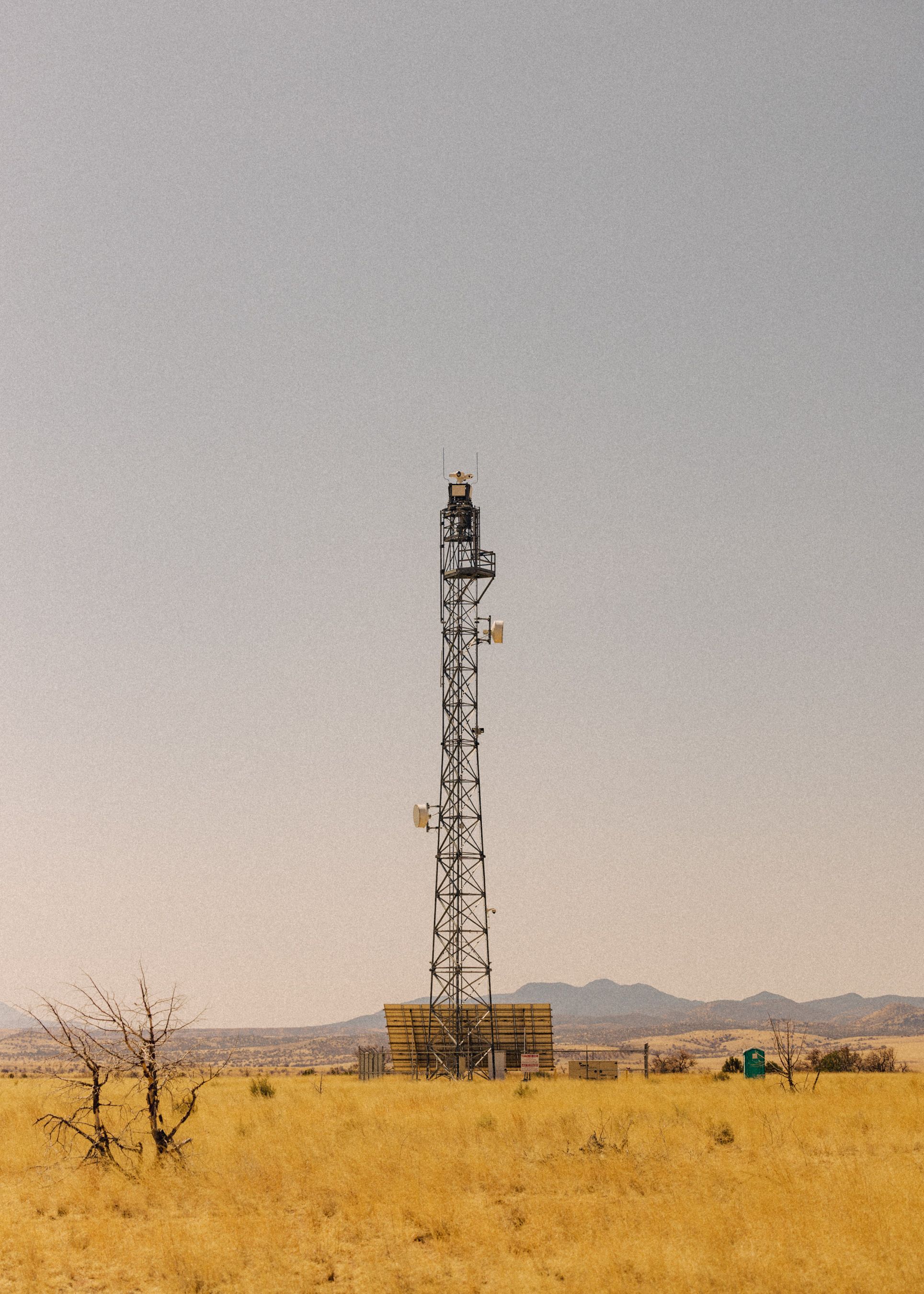 Communication tower in desert landscape with mountains in background