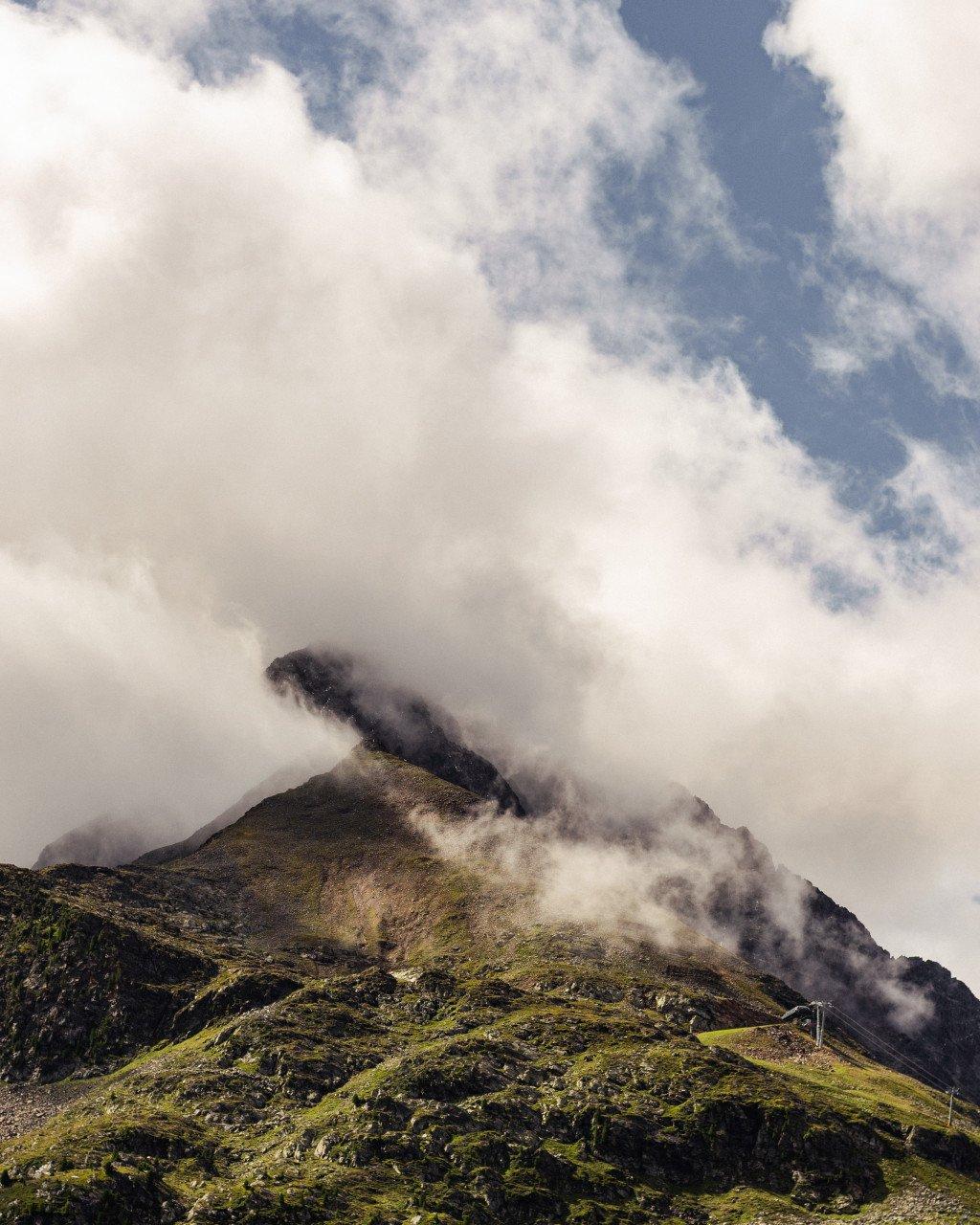 Mountain landscape with clouds rolling over green hills and peaks