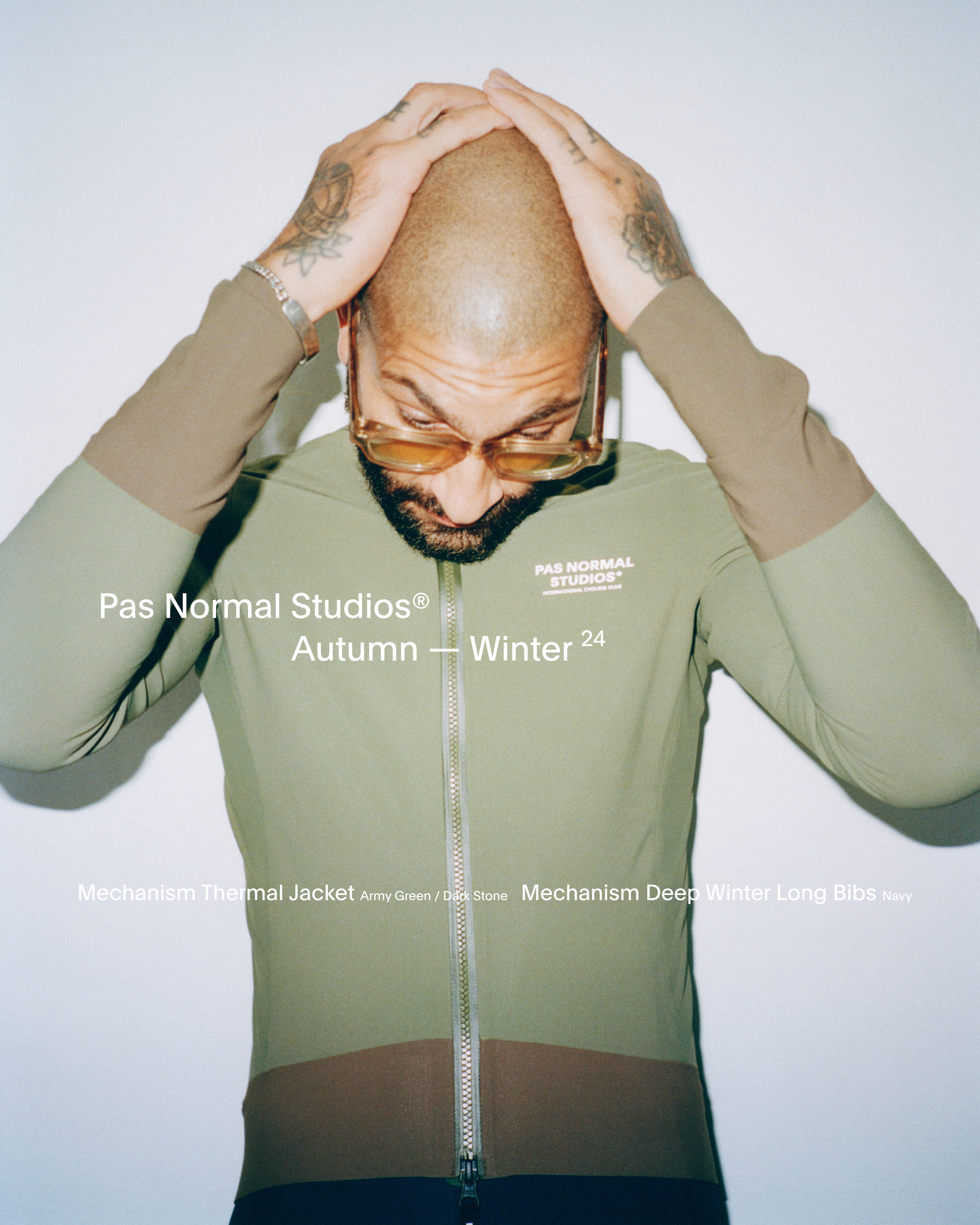 Model wearing Mechanism Thermal Jacket in army green with hands on head, chest branding visible
