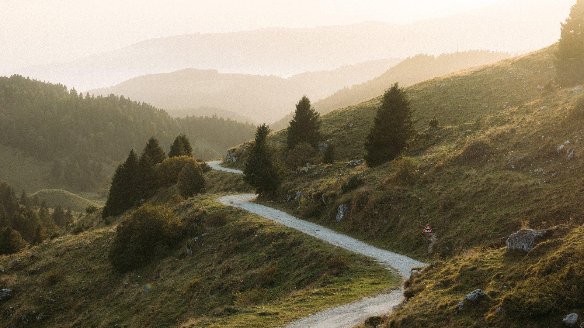 Winding mountain road through rolling hills at golden hour
