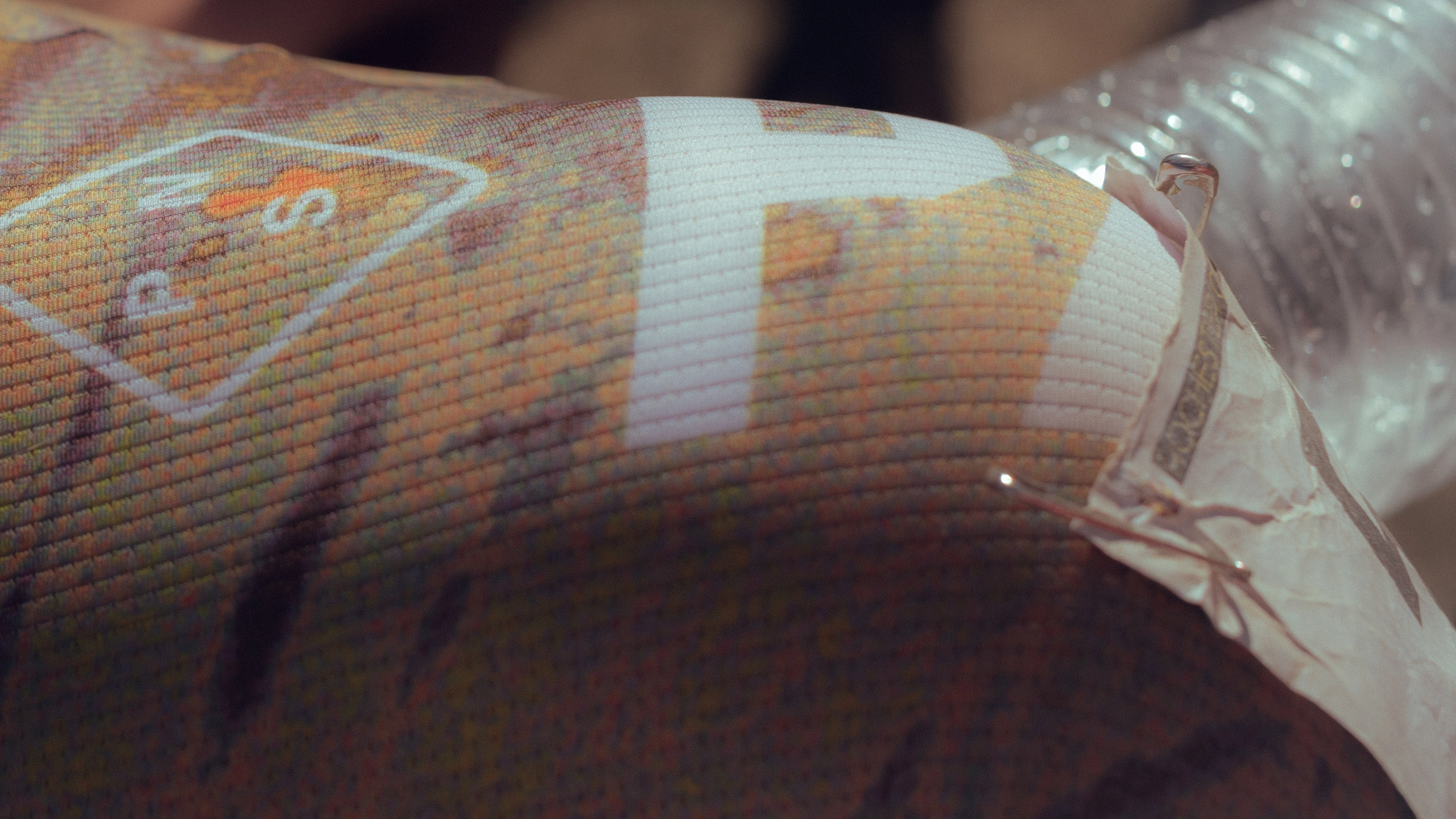 White STFR Mechanism bibs, detail view of textured fabric with colorful pixelated pattern