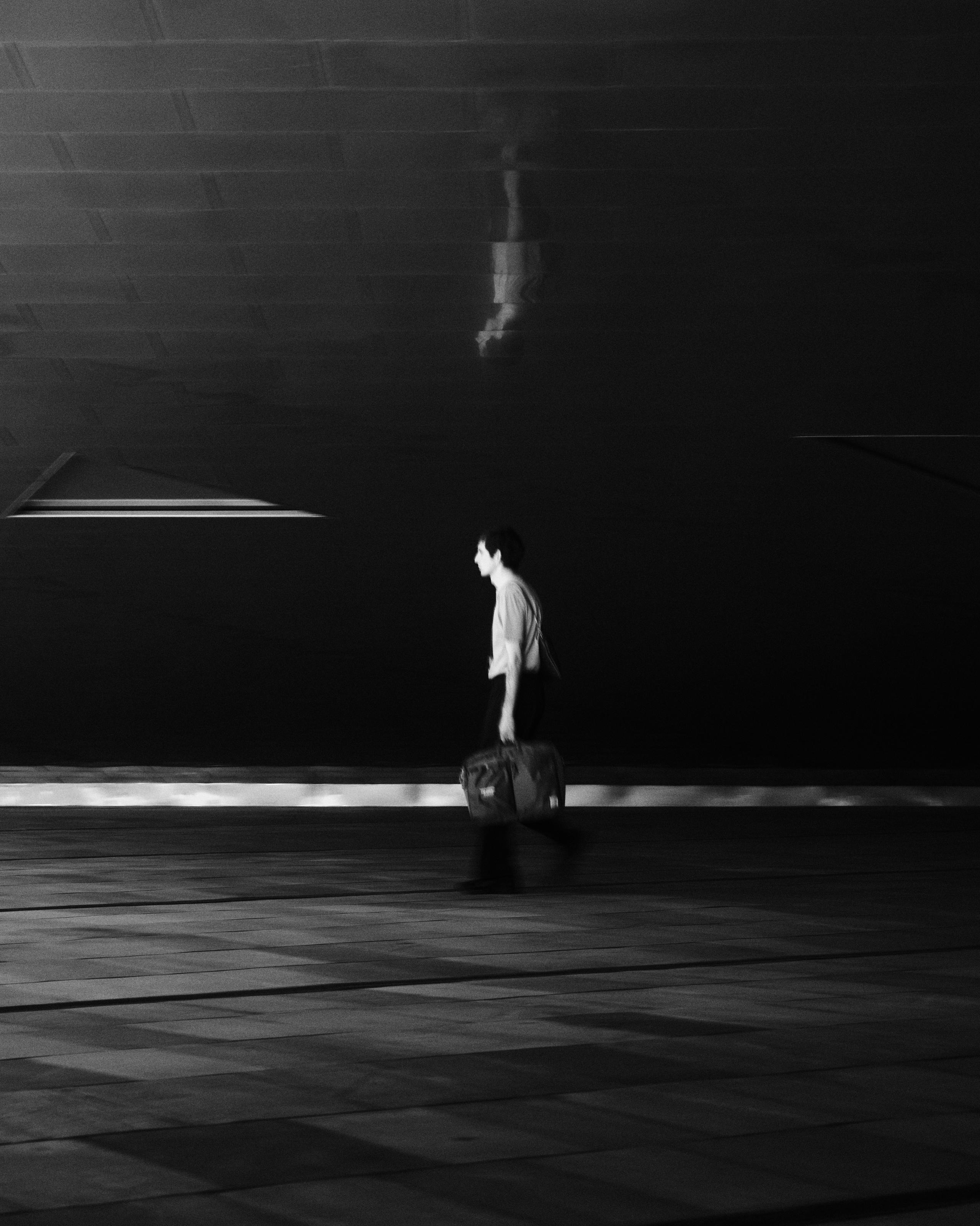 Model wearing white cycling apparel walking through urban tunnel in black and white photograph