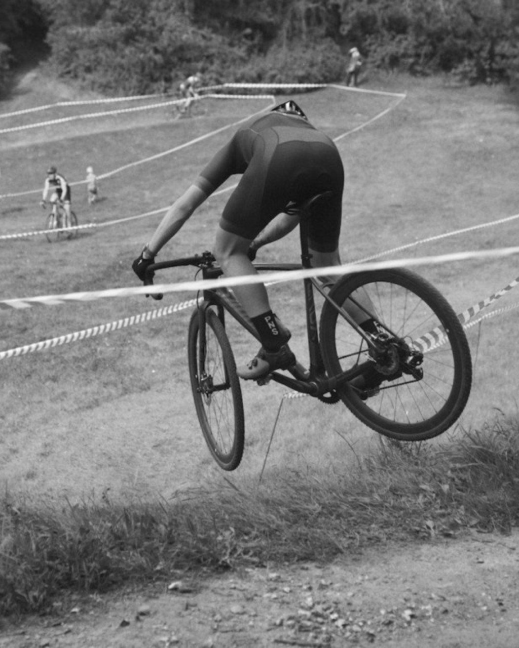 Cyclist in aerodynamic position on time trial bike at velodrome in black and white
