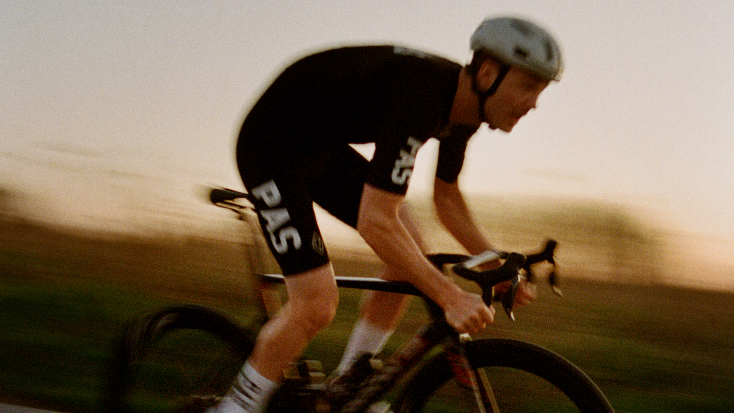 Black PAS Mechanism Pro cycling jersey on model in aerodynamic position with white logo