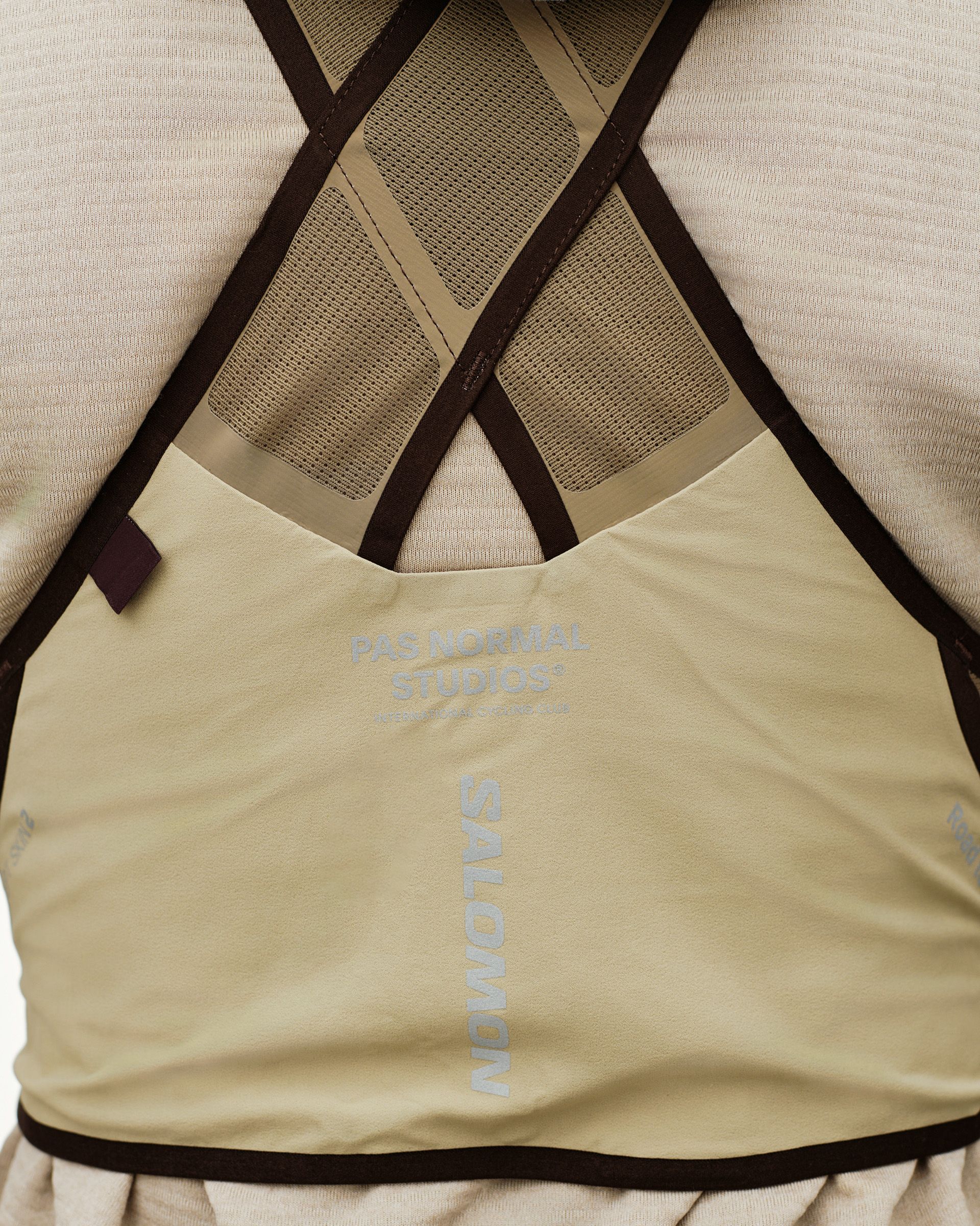 Light Brown Salomon GRAVEL CONCEPT SKIN 2 vest, rear detail on model with crossed straps and mesh back panel
