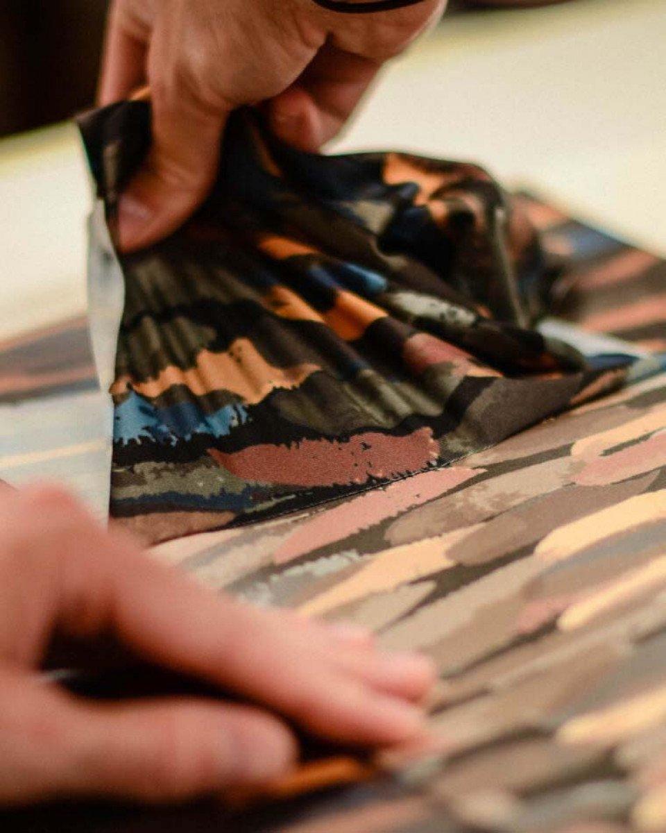 Model wearing abstract print cycling jersey with multicolored brushstroke pattern in blue, orange, and pink tones