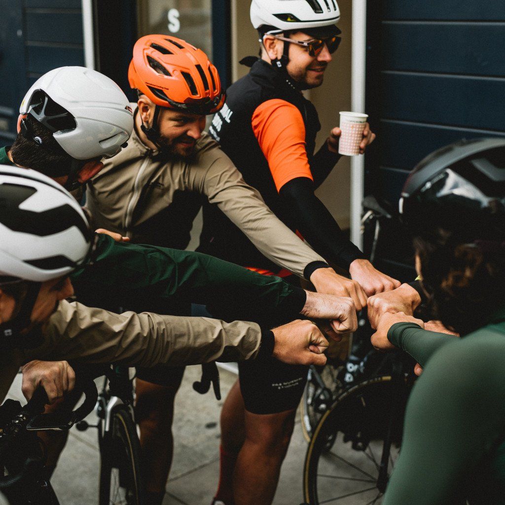 Cyclists in helmets doing team hand stack before ride in Sonoma