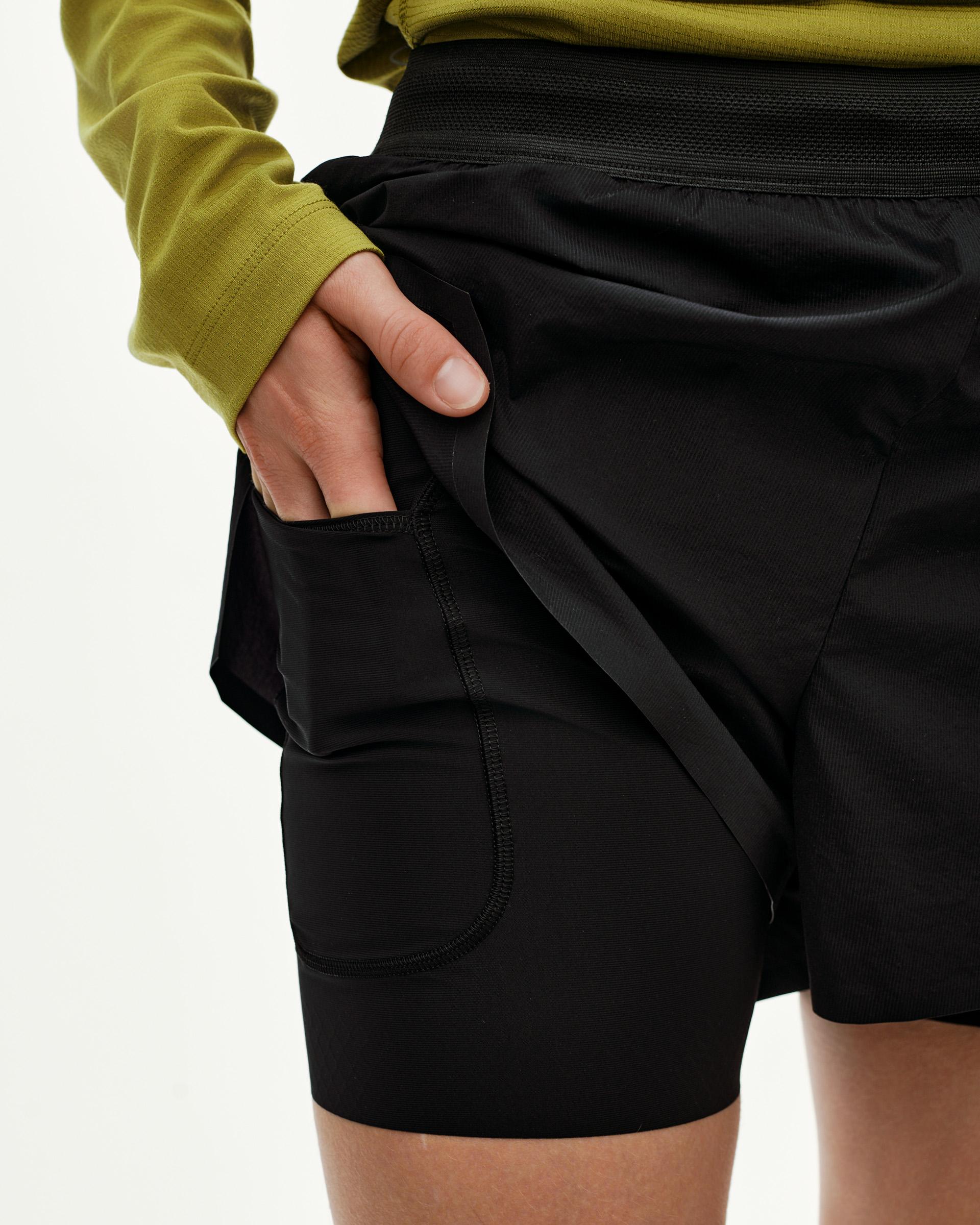 Black Balance 2-in-1 shorts, detail view on model showing side pocket with hand inserted