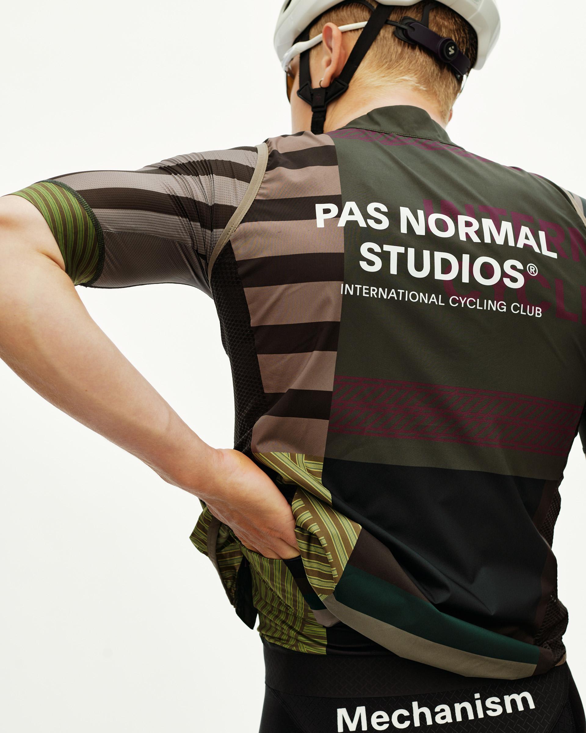 International Earth khaki Mechanism Stow Away cycling gilet on model, rear view with multicolour stripe print and back logo