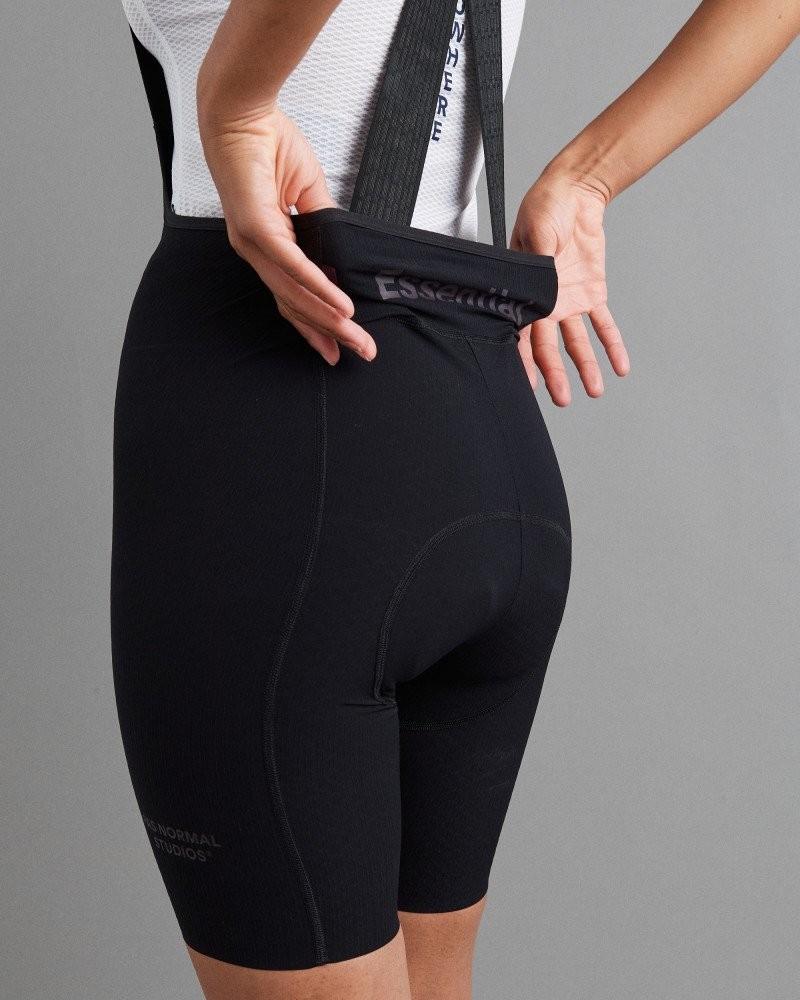 Black Essential Light cycling bibs on model showing rear pocket with reflective logo detail