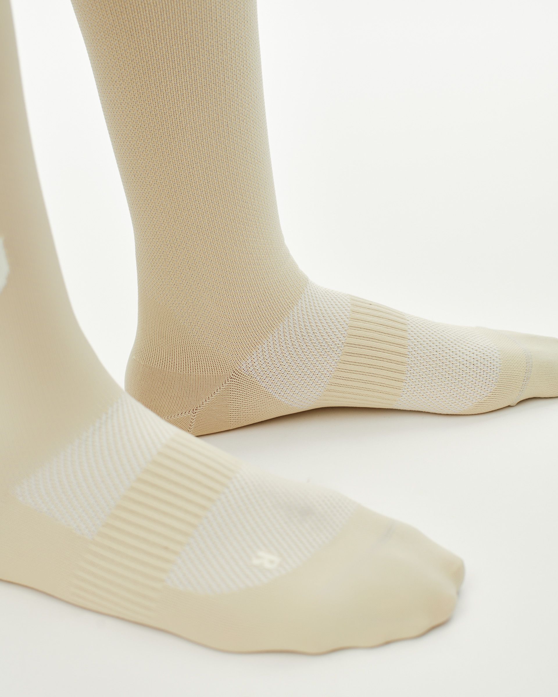 Cream PAS Race cycling socks on model with ribbed cuff and mesh foot panel