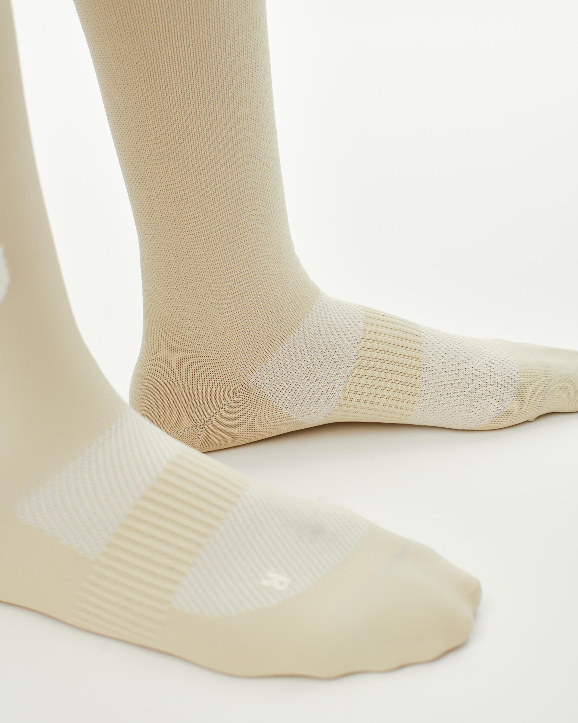 Cream PAS Race cycling socks on model with ribbed cuff and mesh foot panel