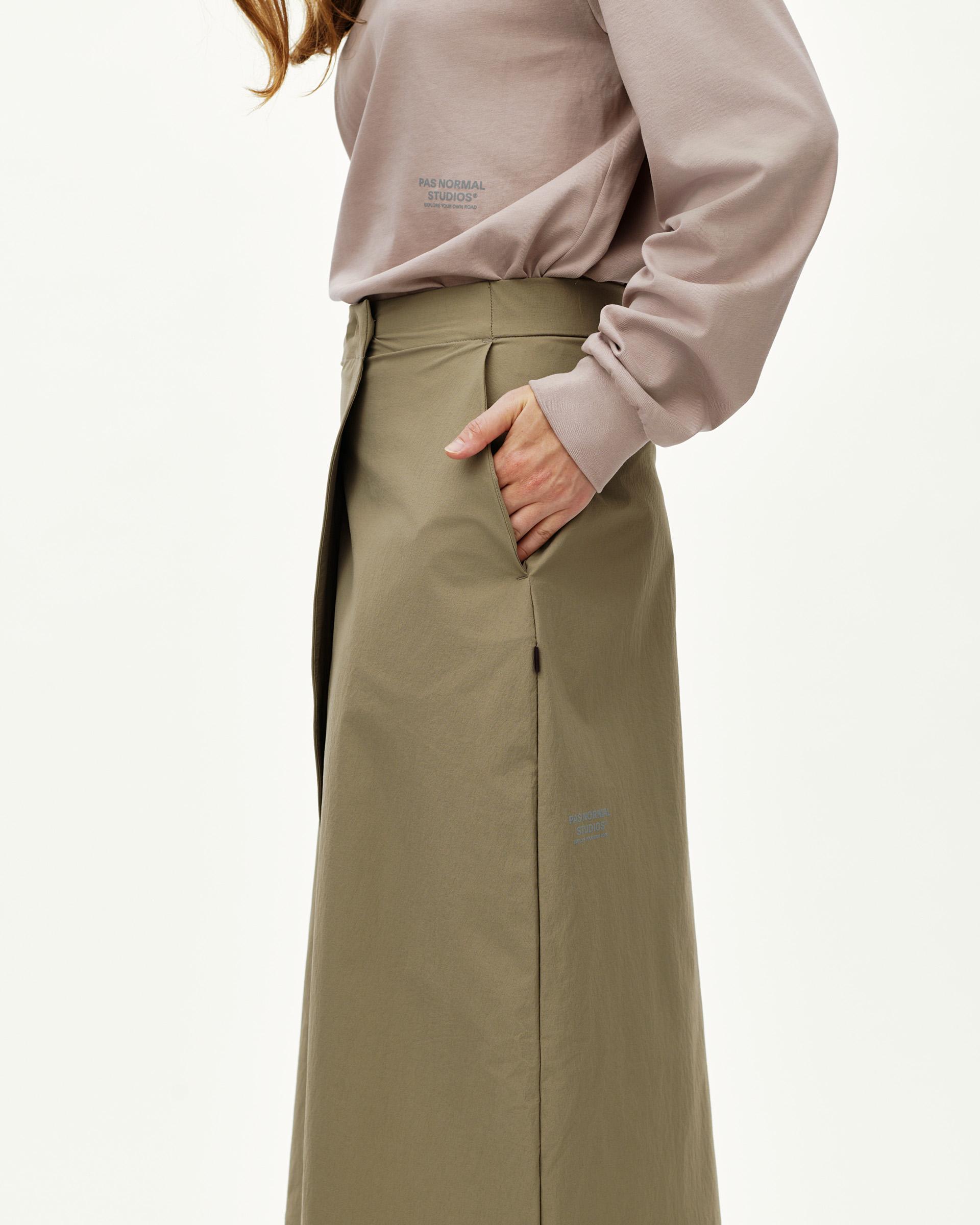 Dusty Earth khaki Off-Race women's tech skirt on model, side view with hand in pocket and back vent