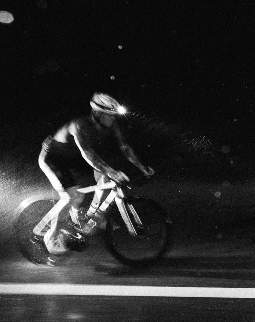 Cyclist riding at night in black and white with headlamp illumination