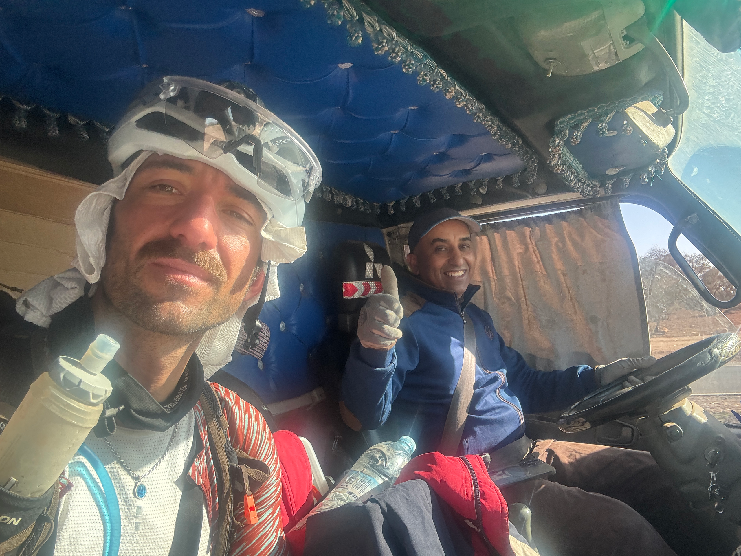 Two cyclists in helicopter wearing racing gear including white helmet and blue jersey
