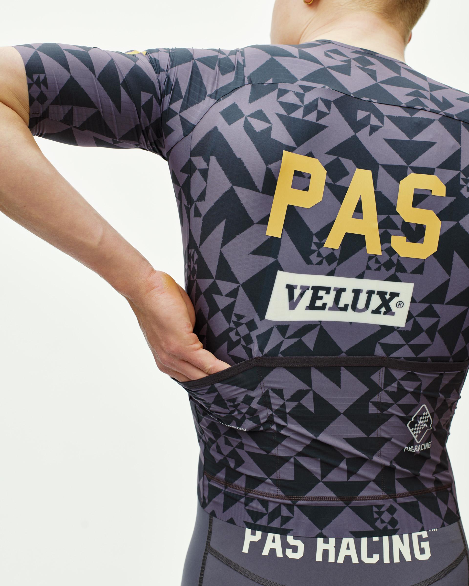 Origami Grey PAS Mechanism Pro cycling jersey on model, rear view with geometric print and gold PAS chest logo