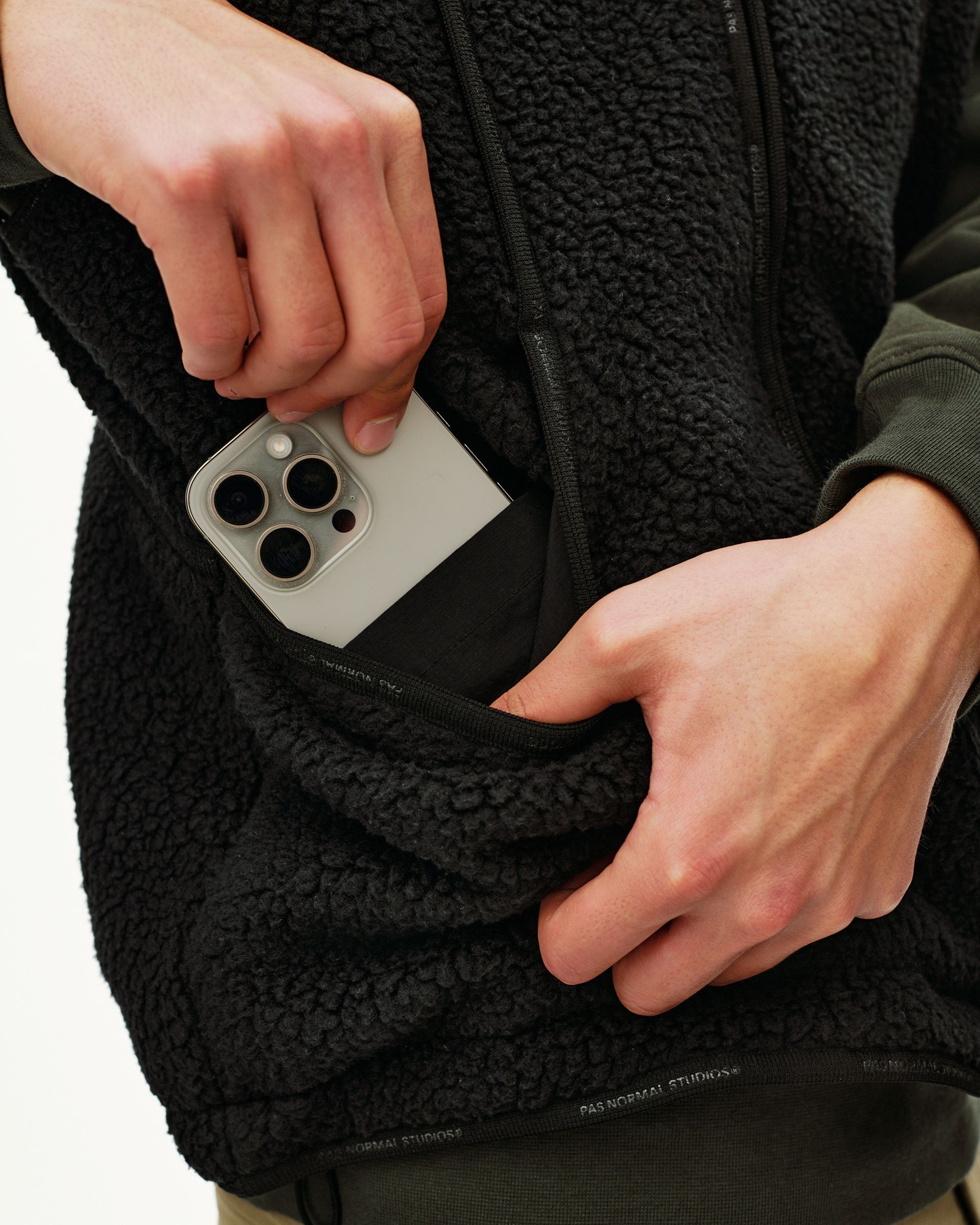 Black Off-Race Pile Fleece vest, detail view of side pocket with phone being inserted