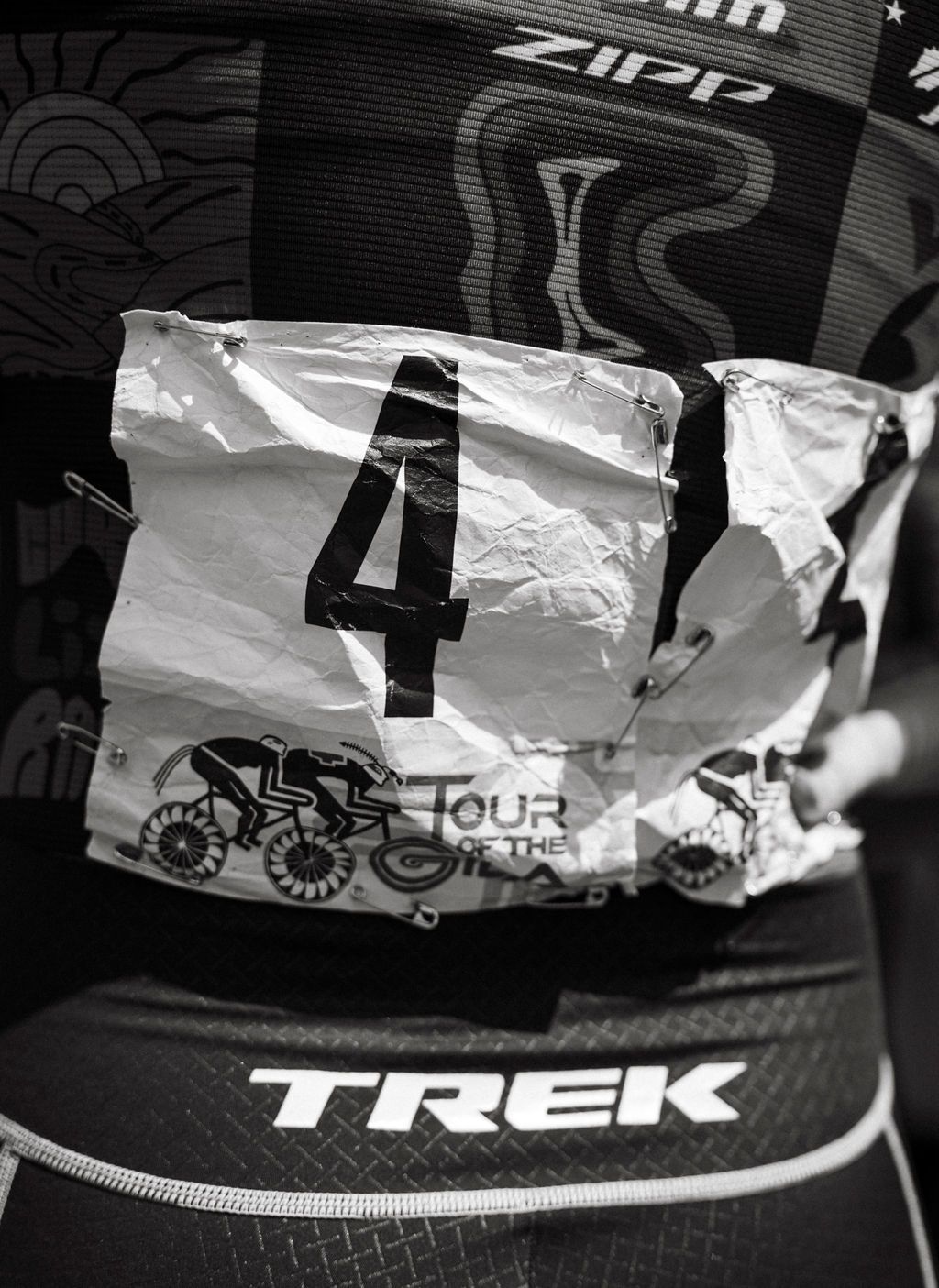 White cycling race number 4 with Tour of the Gila branding pinned to cycling jersey