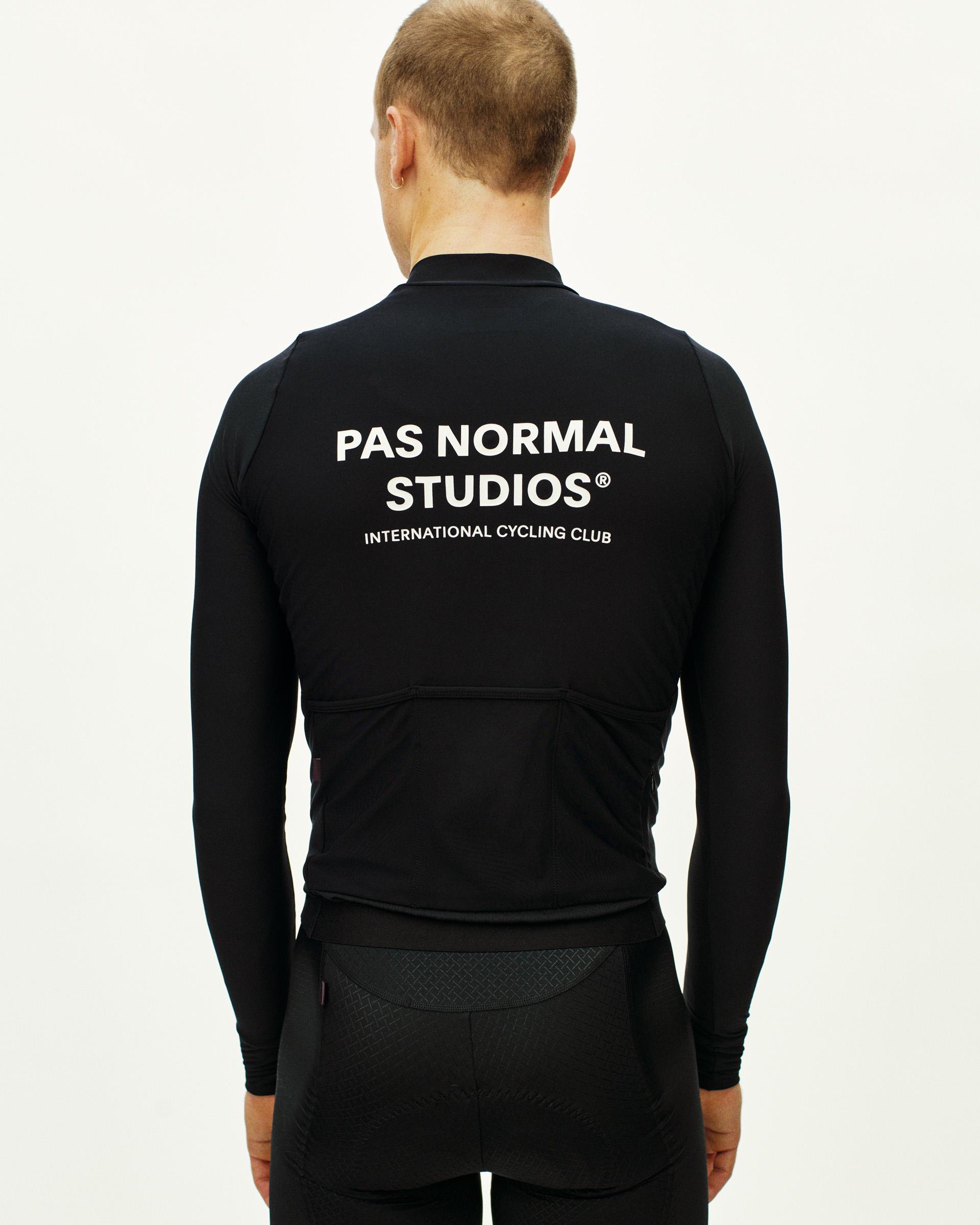 Black Mechanism long sleeve cycling jersey, rear view on model with white brand text and rear pockets