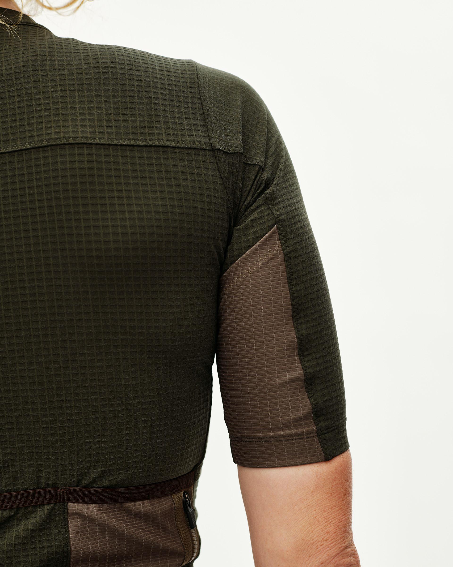 Dark Olive Escapism women's cycling jersey, rear detail on model with grid-texture fabric and contrast brown side panel
