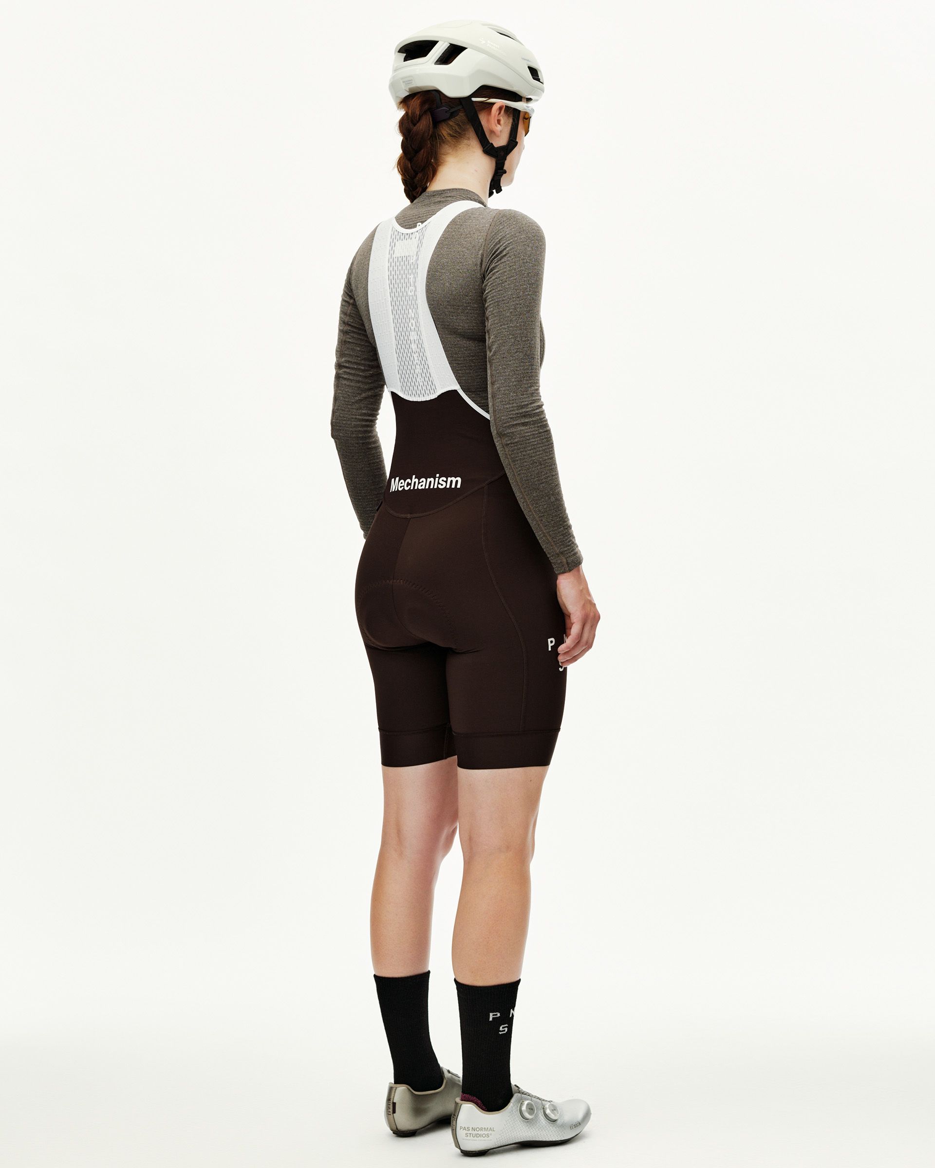 Dark Coffee Mechanism women's cycling bibs, rear view on model with white mesh bib straps and Mechanism logo