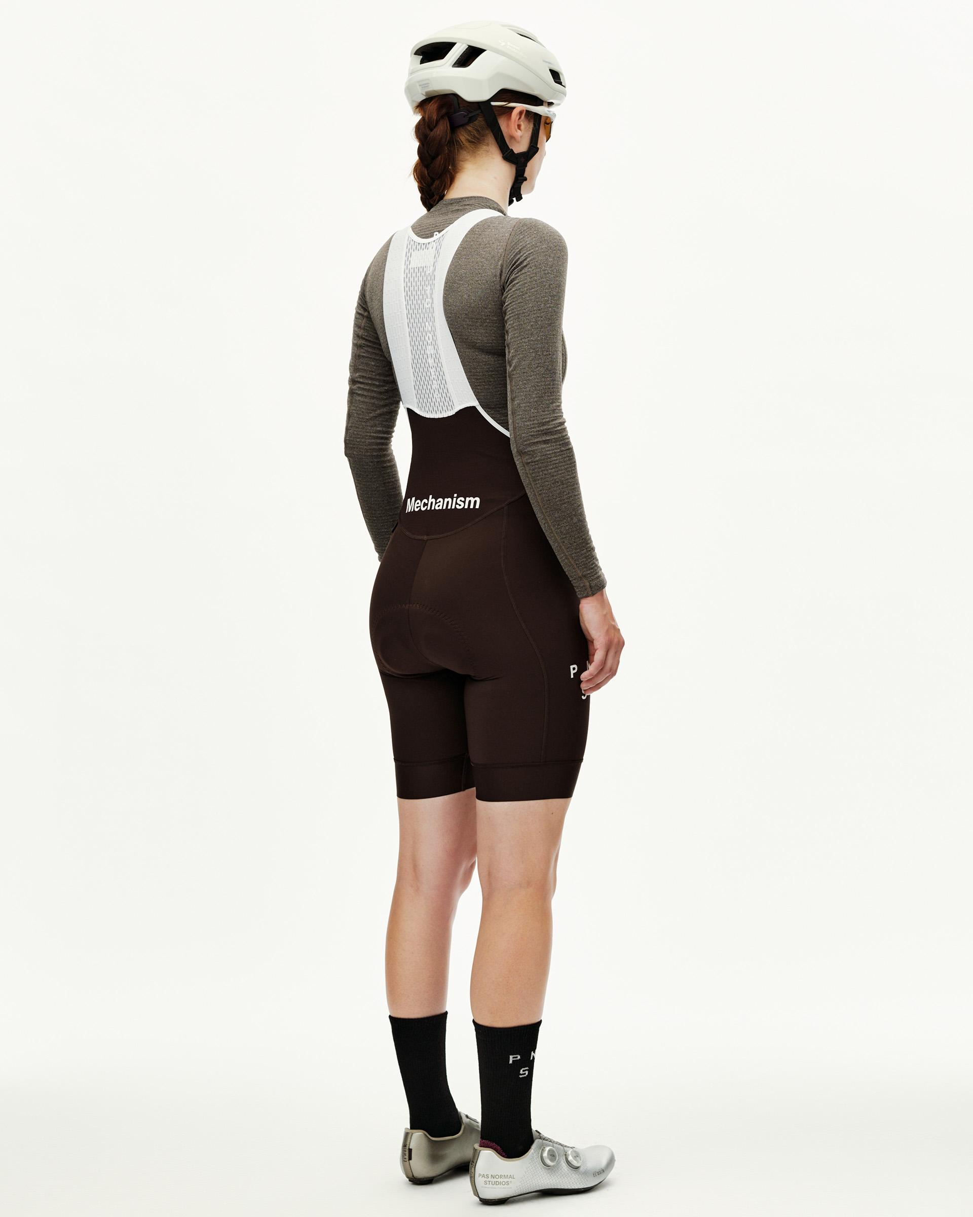 Dark Coffee Mechanism women's cycling bibs, rear view on model with white mesh bib straps and Mechanism logo