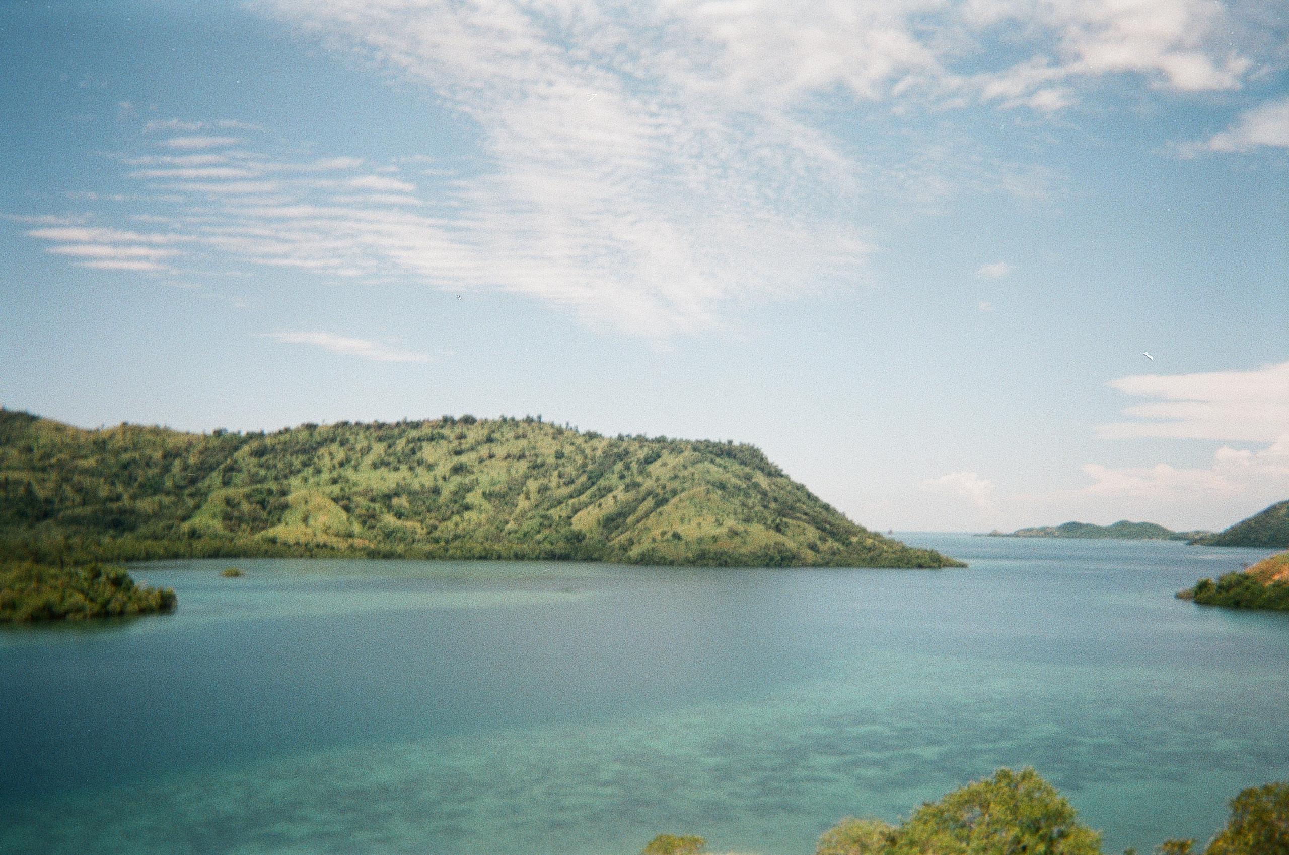 Scenic lake view with forested hills and cloudy sky in Flores, Indonesia