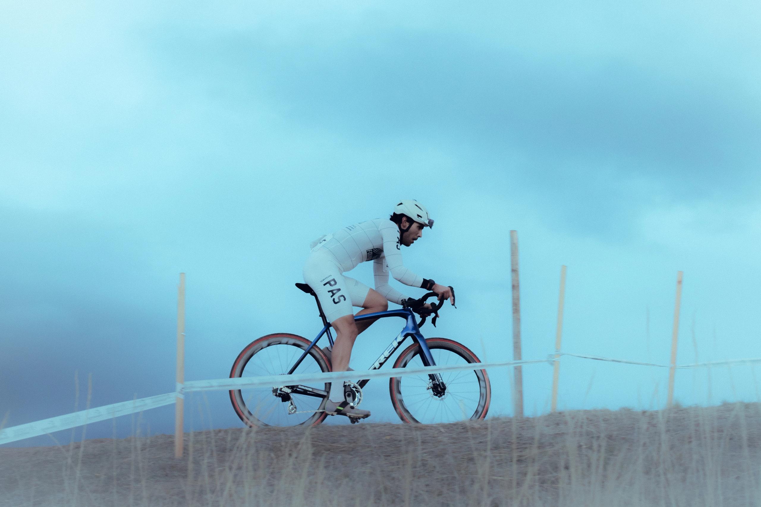 Cyclist in white aerodynamic suit on time trial bike in foggy conditions