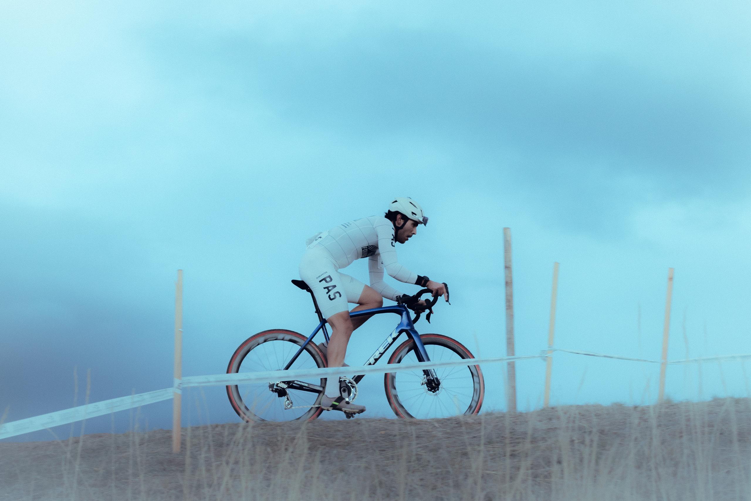 Cyclist in white aerodynamic suit on time trial bike in foggy conditions