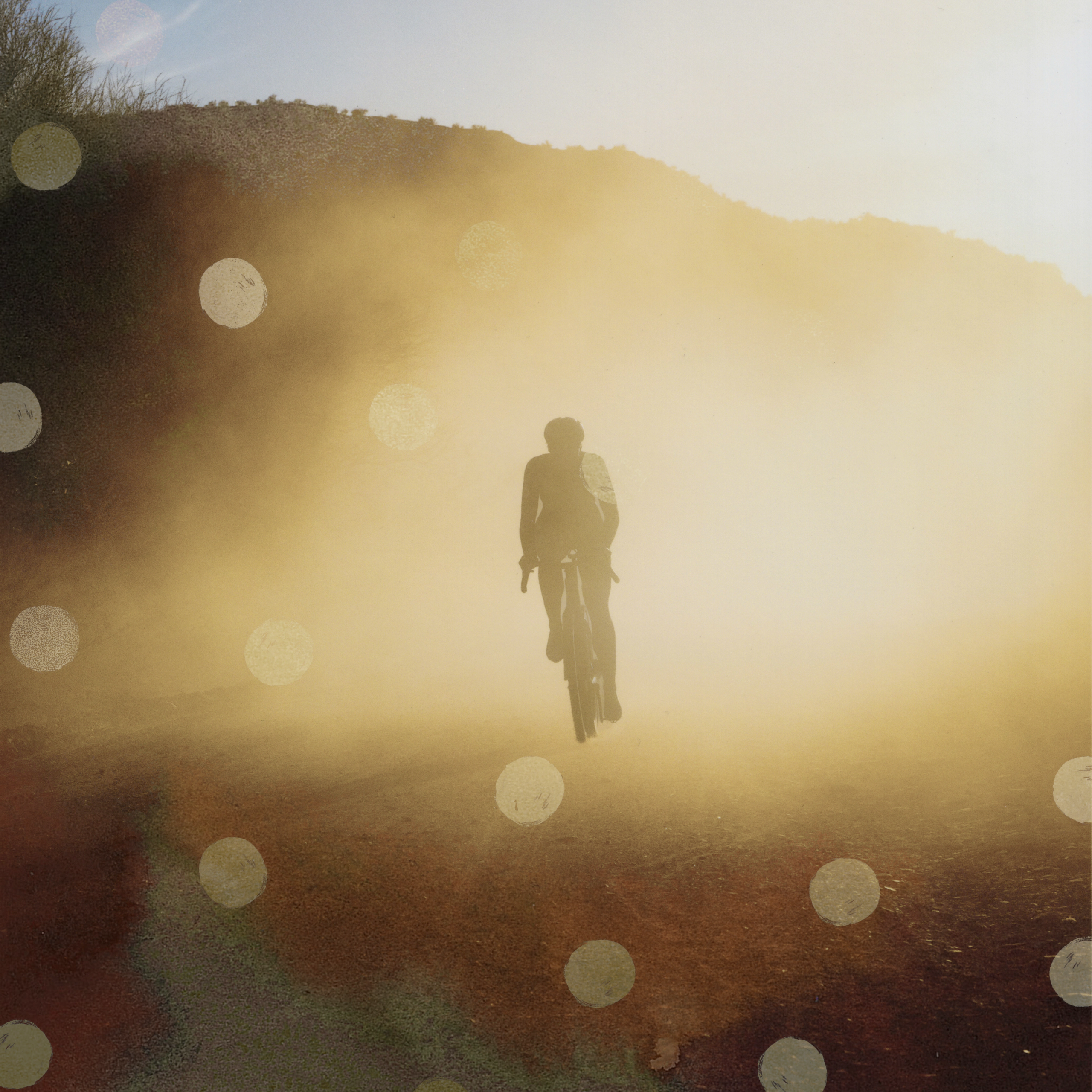 Black T.K.O. Balance cap worn by cyclist in golden hour landscape with lens flare effects