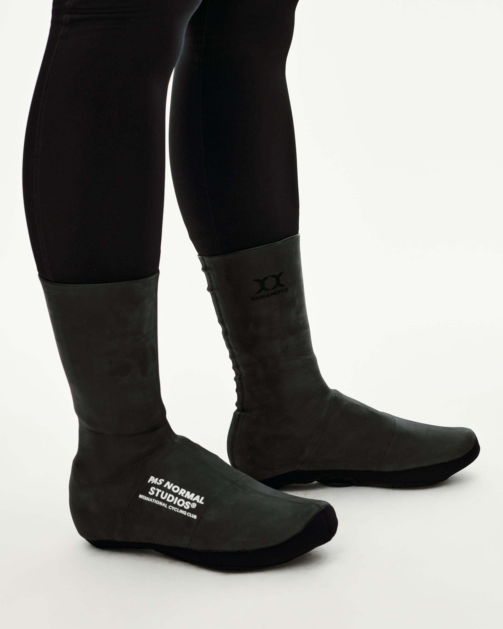 Black Logo Heavy cycling overshoes on model, side view with white chest logo print and Yamamoto branding