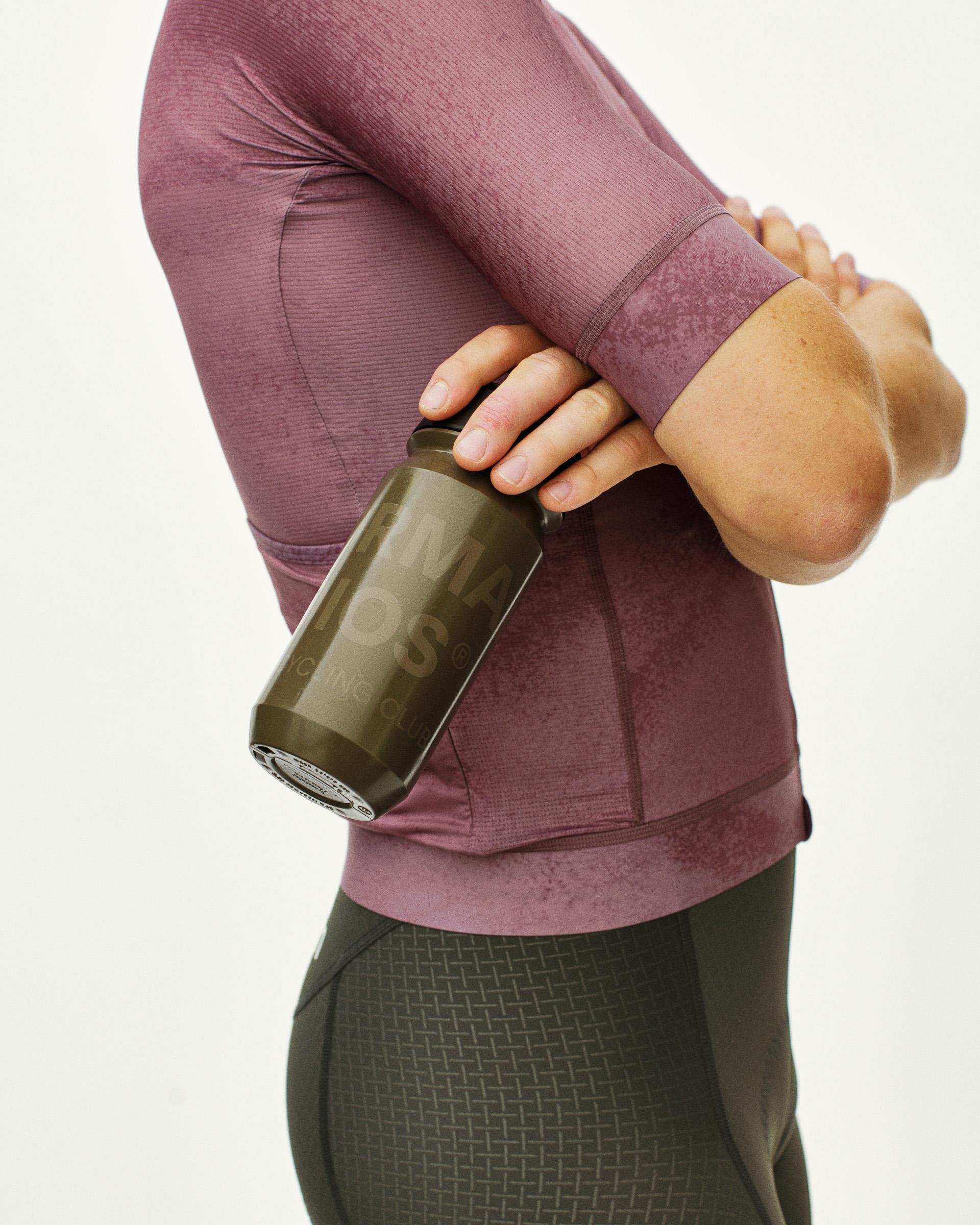 Brown Essential Logo water bottle on model with green tinted glass design