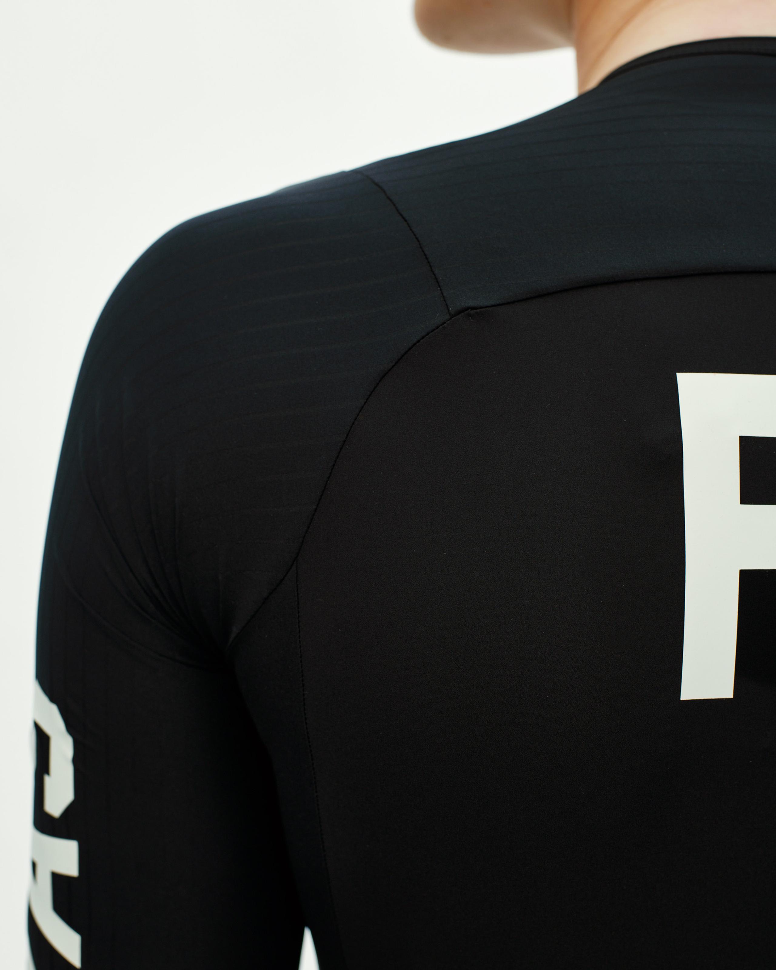 Black PAS Mechanism Pro cycling jersey on model, rear view with white logo print