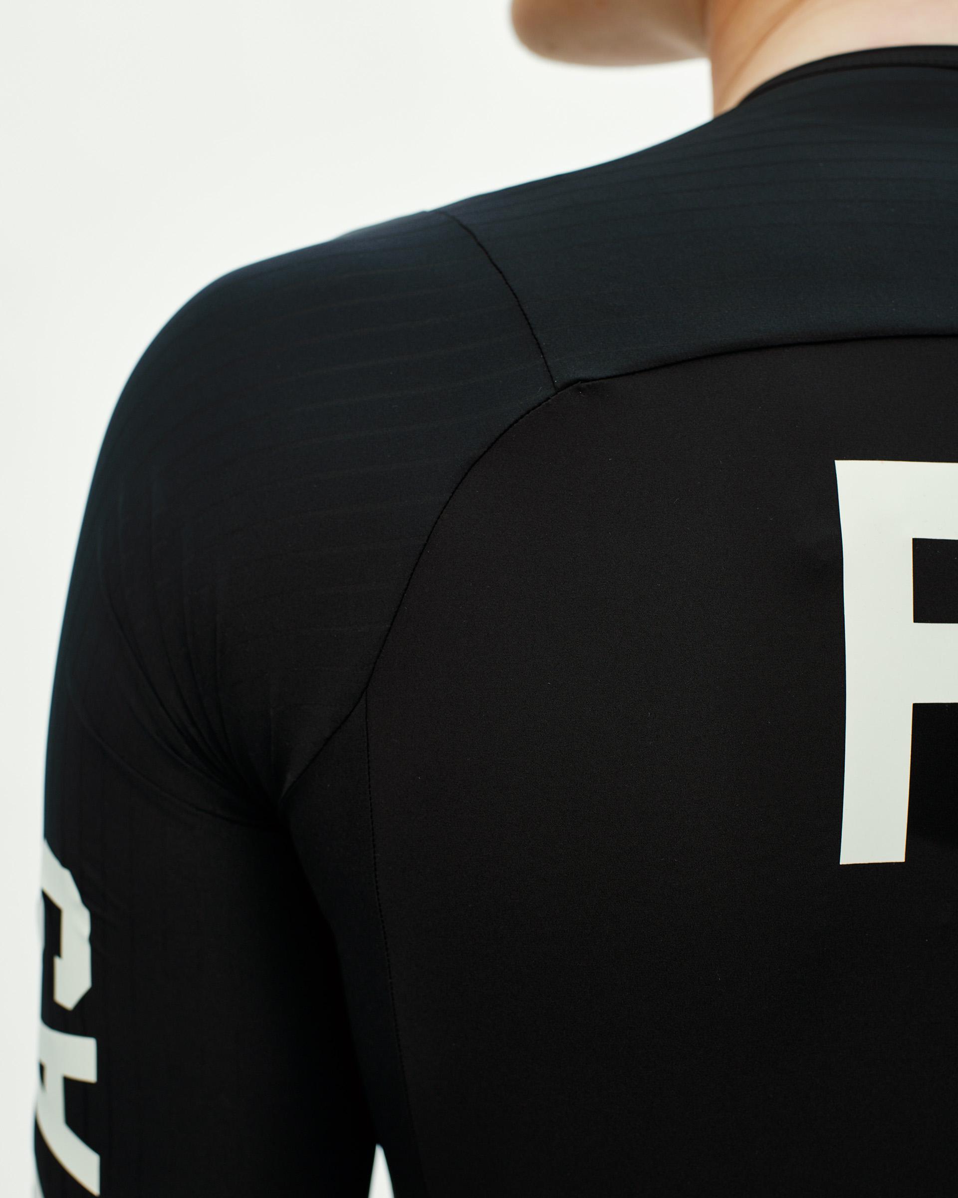 Black PAS Mechanism Pro cycling jersey on model, rear view with white logo print