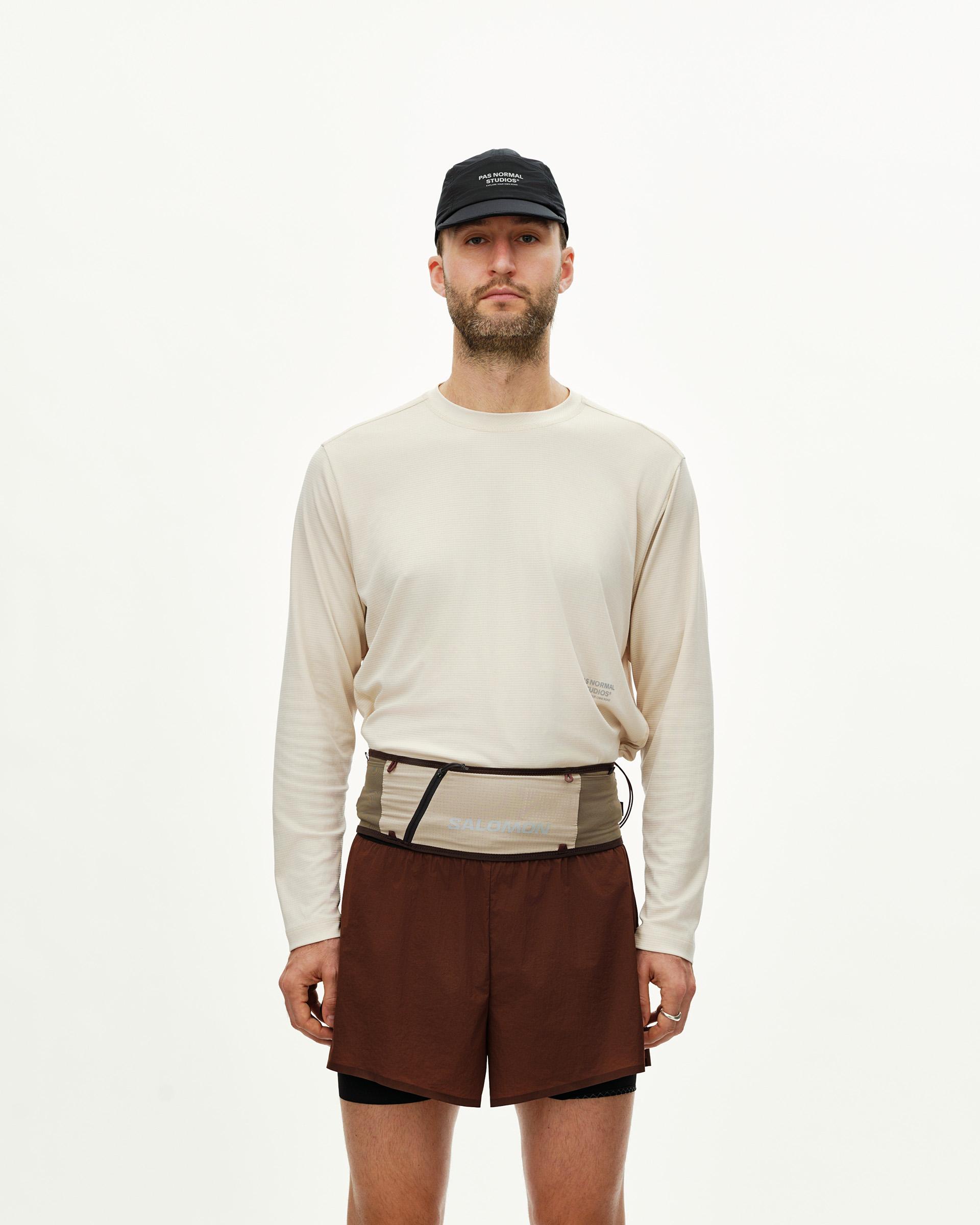 Light Brown Salomon S/LAB Belt on model, front view worn over cream long sleeve top with dark brown shorts