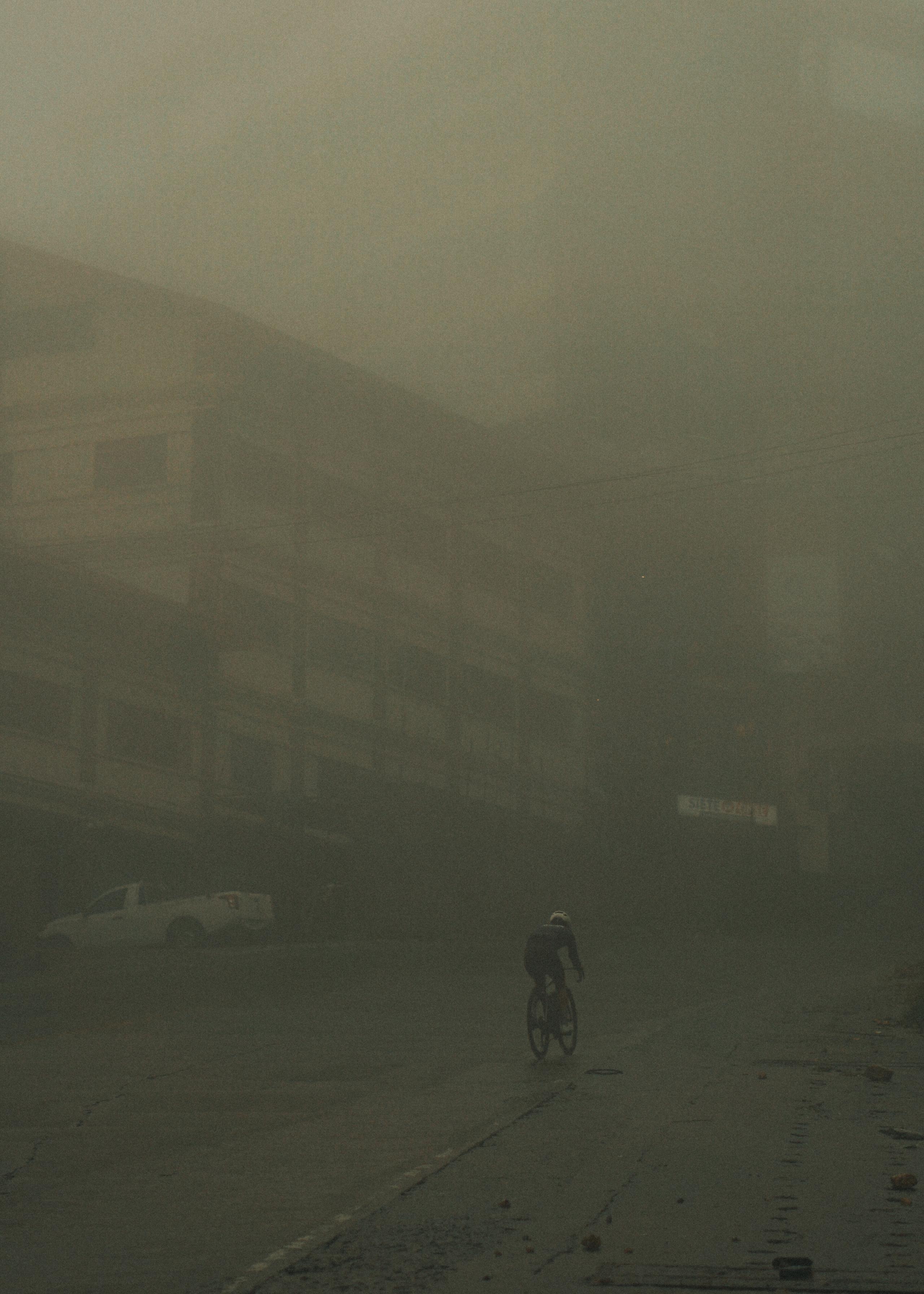 Cyclist riding through misty mountain landscape in low visibility conditions