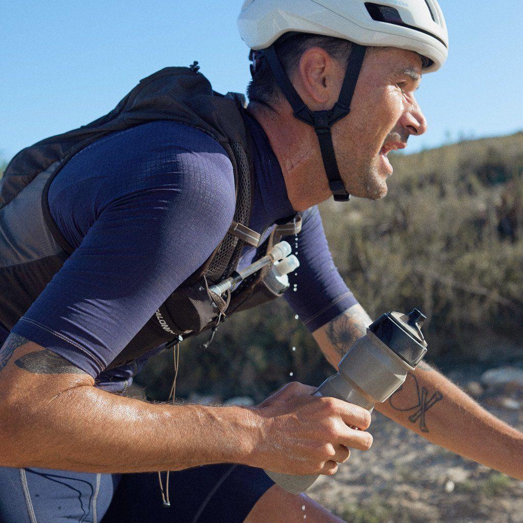 Model wearing blue cycling gear with white helmet on gravel bike outdoors