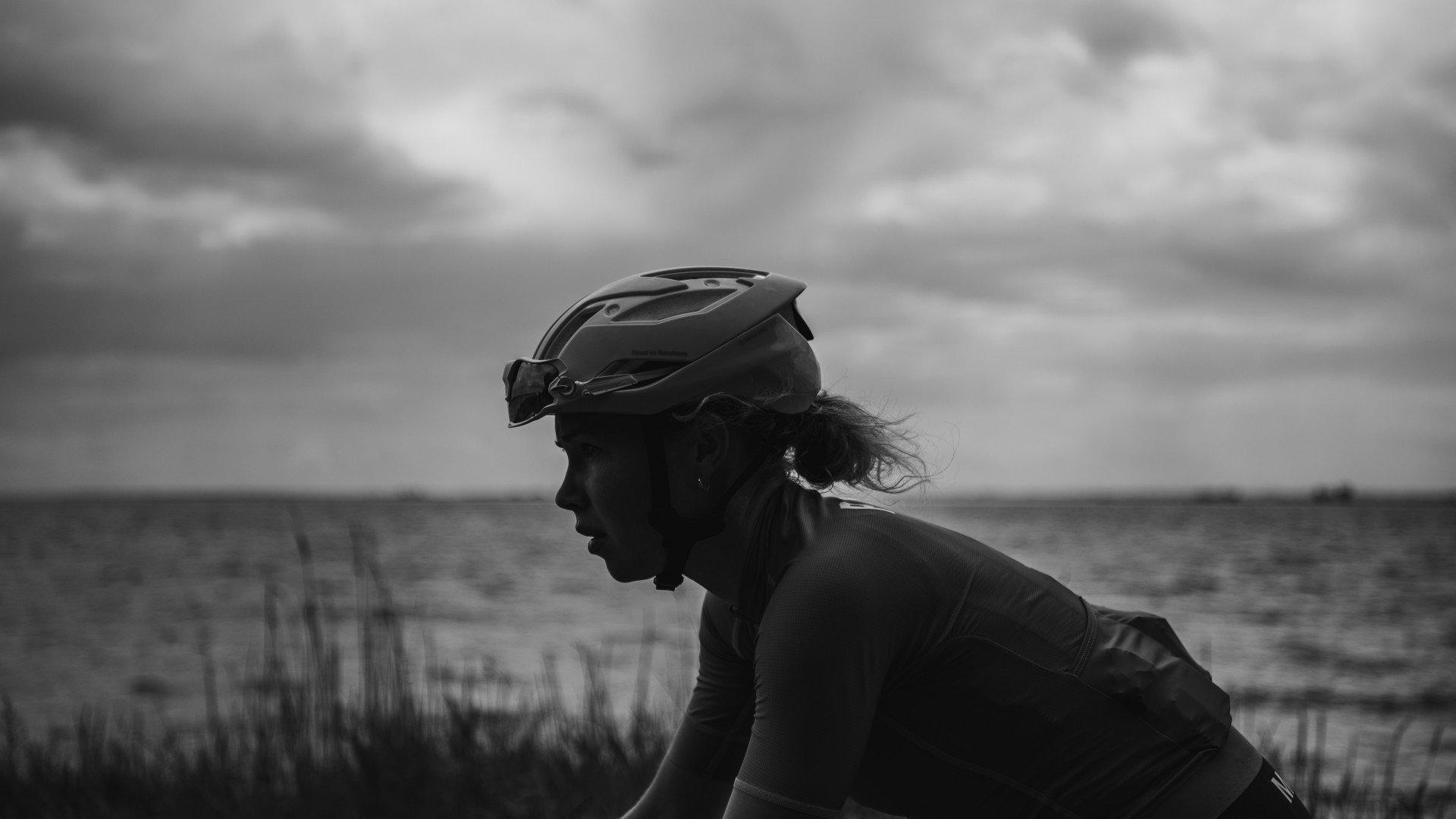Cyclist in helmet riding through countryside in black and white