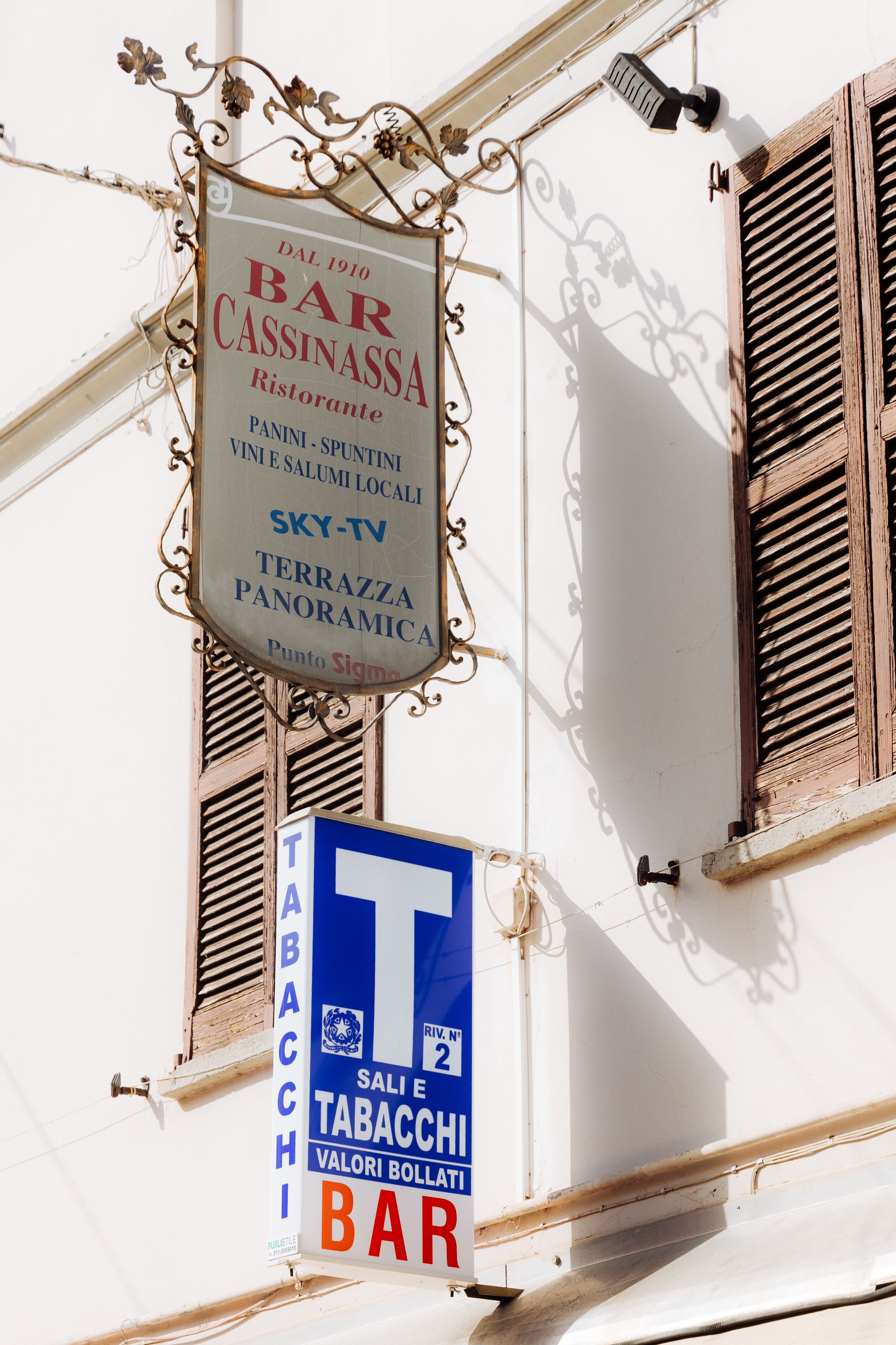 Italian bar and restaurant signs on white building with wooden shutters