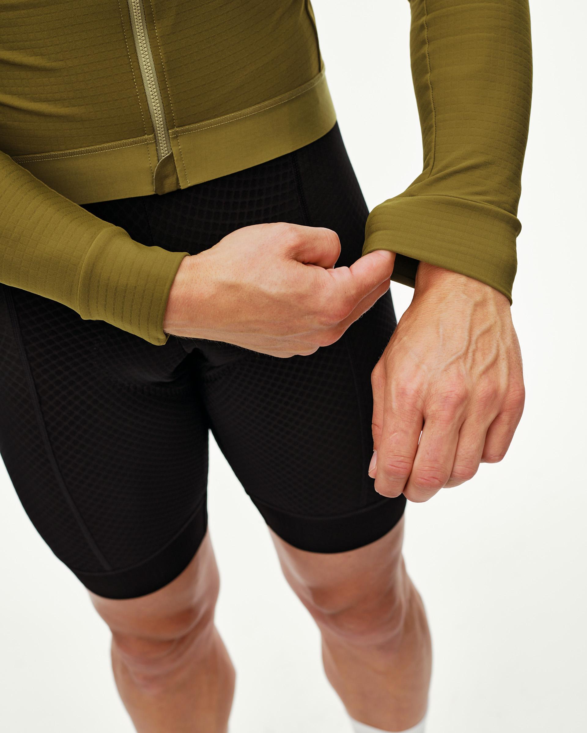 Khaki Green Essential long sleeve cycling jersey on model, front detail with ribbed cuffs and zip collar