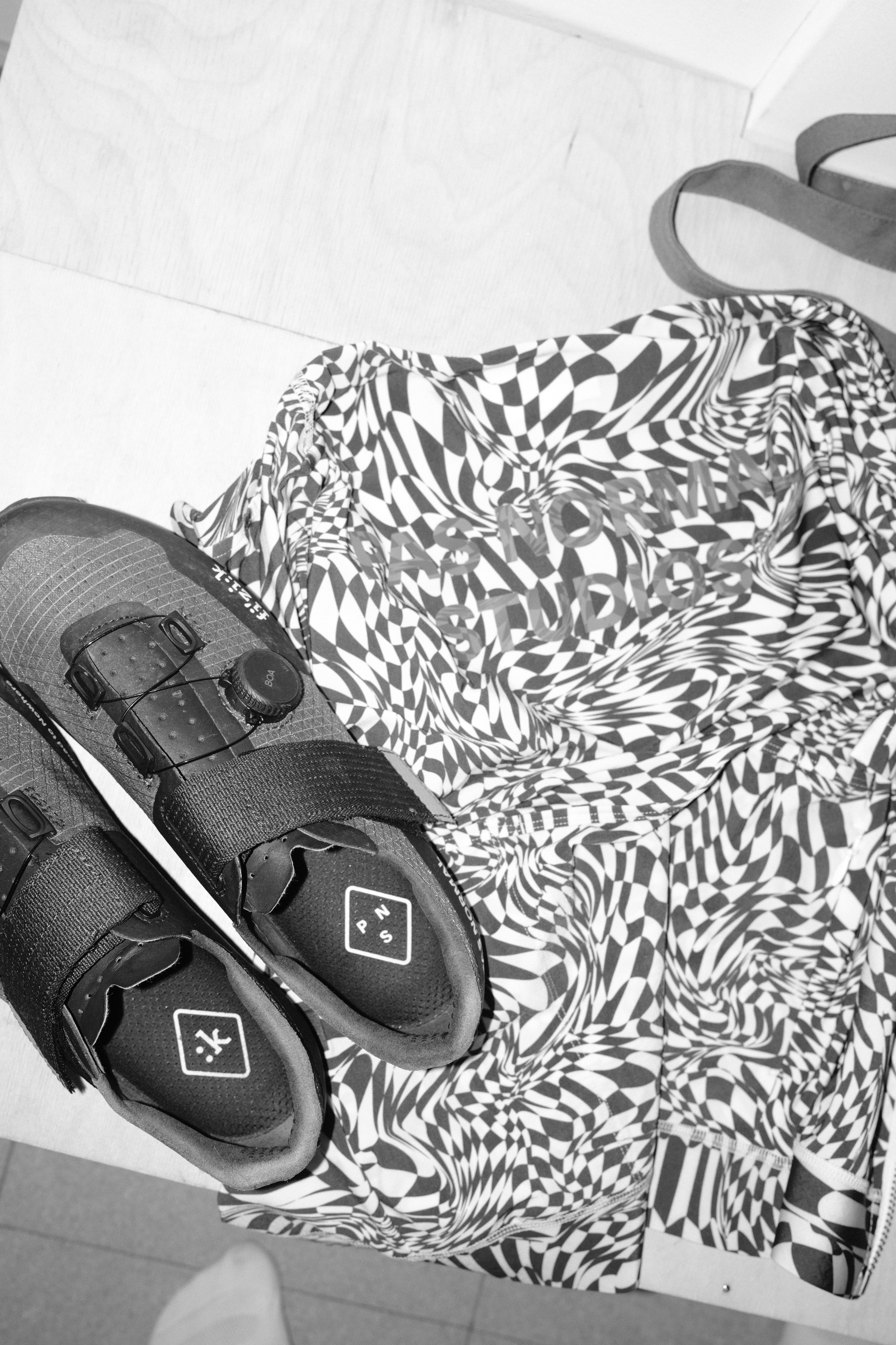 Black and white image of cycling shoes and patterned jersey with geometric print