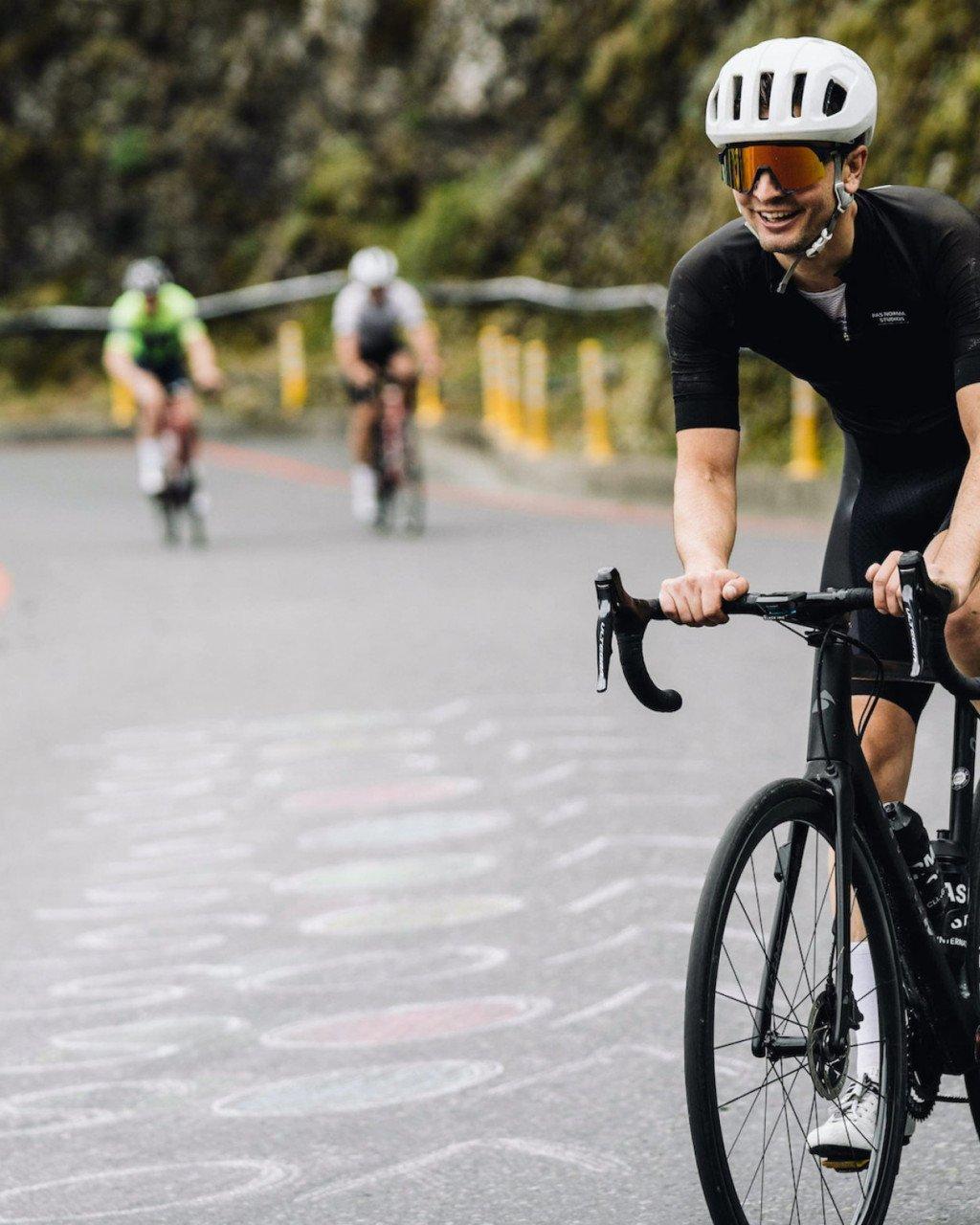 Model wearing black cycling suit with aerodynamic helmet on time trial bike during race