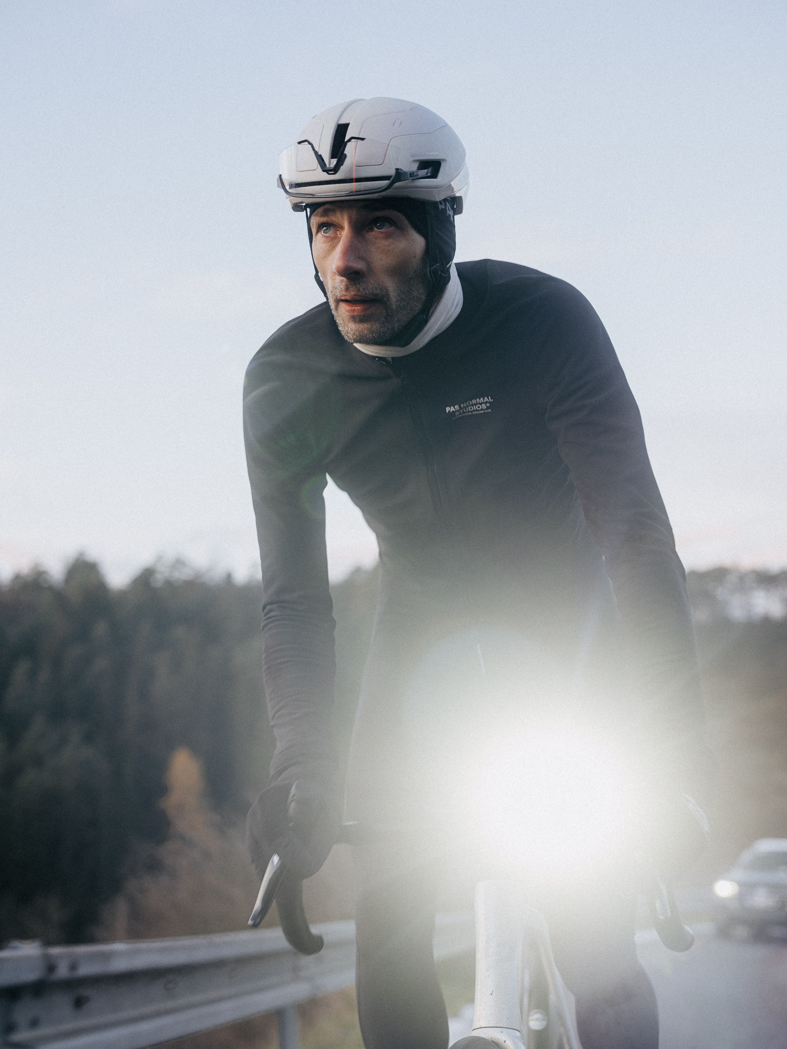 Model wearing dark aero jersey with white time trial helmet in racing position