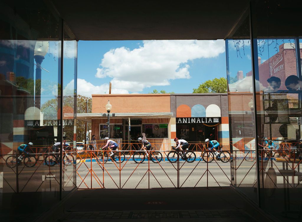 Cyclists racing past storefront windows during Tour of the Gila