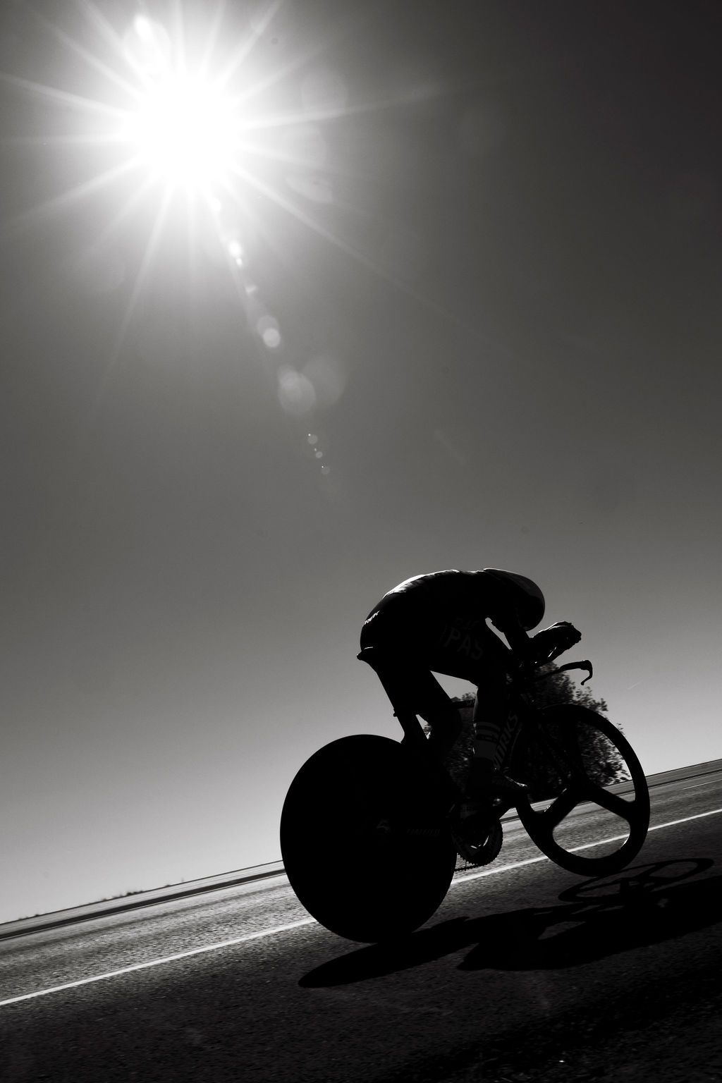 Cyclist silhouetted against bright sun on time trial bike during competition