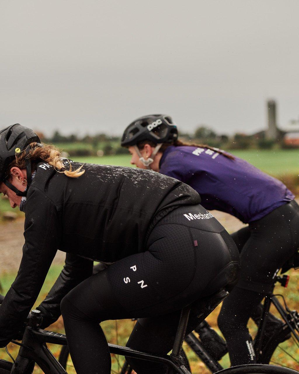 Models wearing black cycling jerseys and shorts during muddy outdoor ride