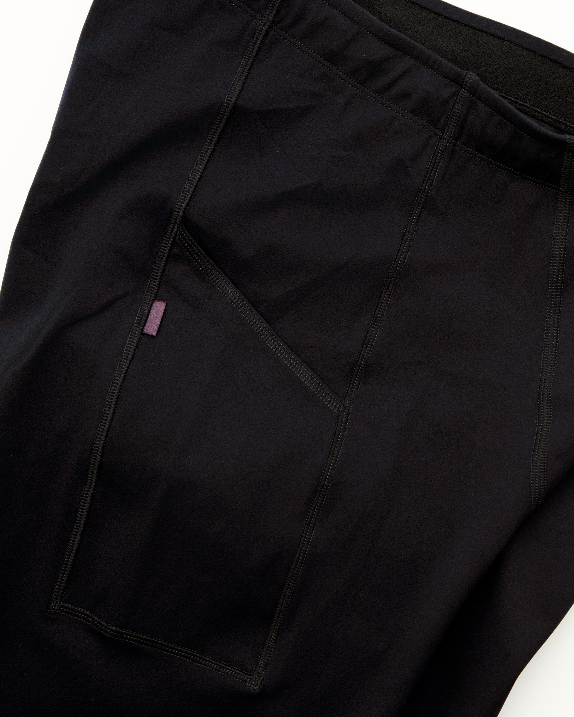 Black cycling tights with side pocket featuring purple accent tab for storing essentials